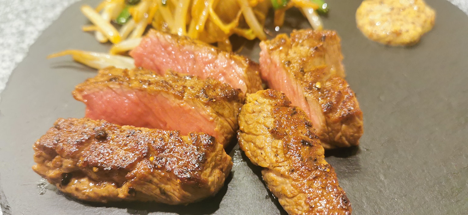 Saftiges Steak auf einem schwarzen Teller mit Beilagensalat serviert