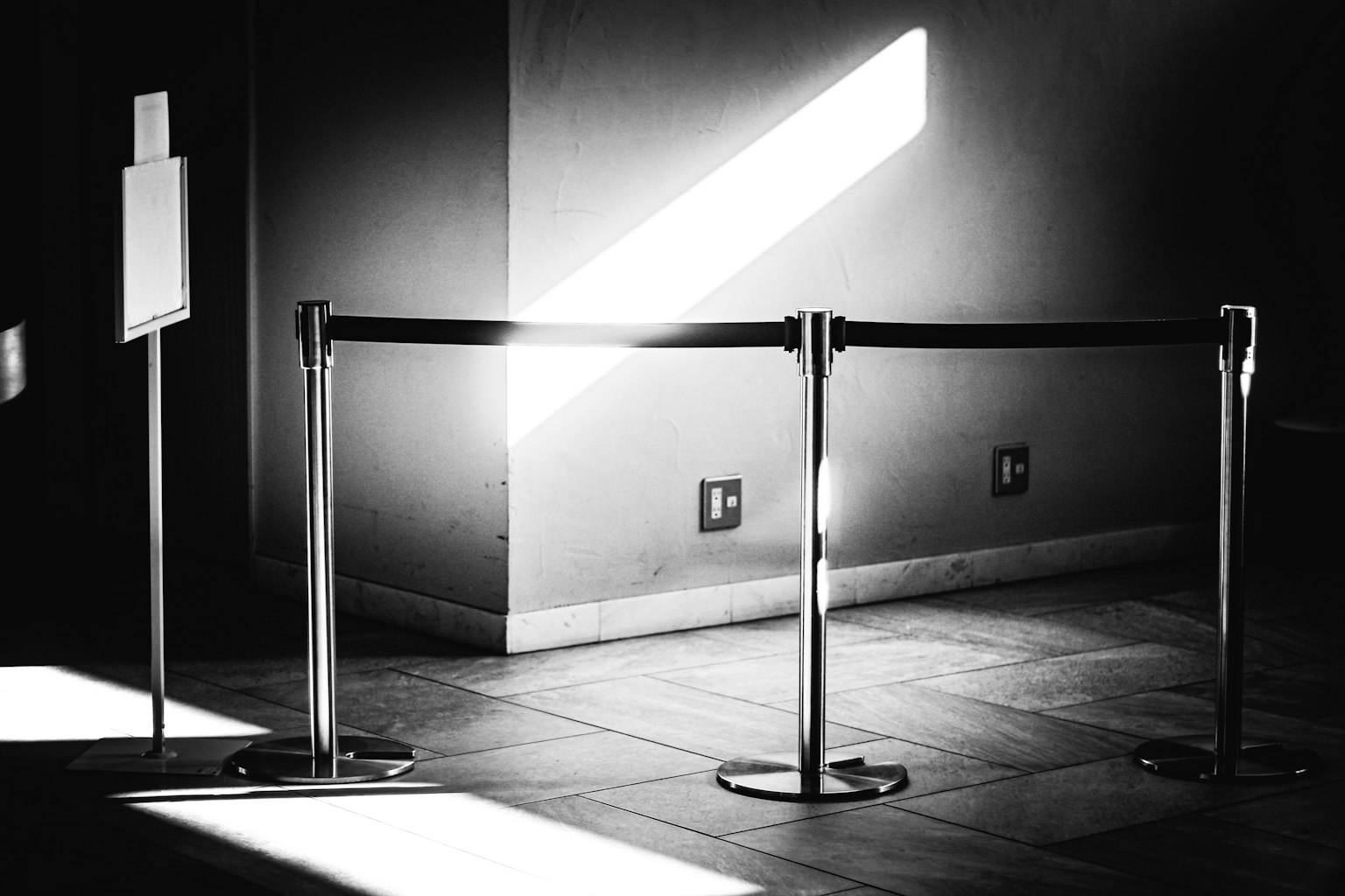 Schwarzweißfoto einer Seilbarriere mit Licht, das von der Seite strömt
