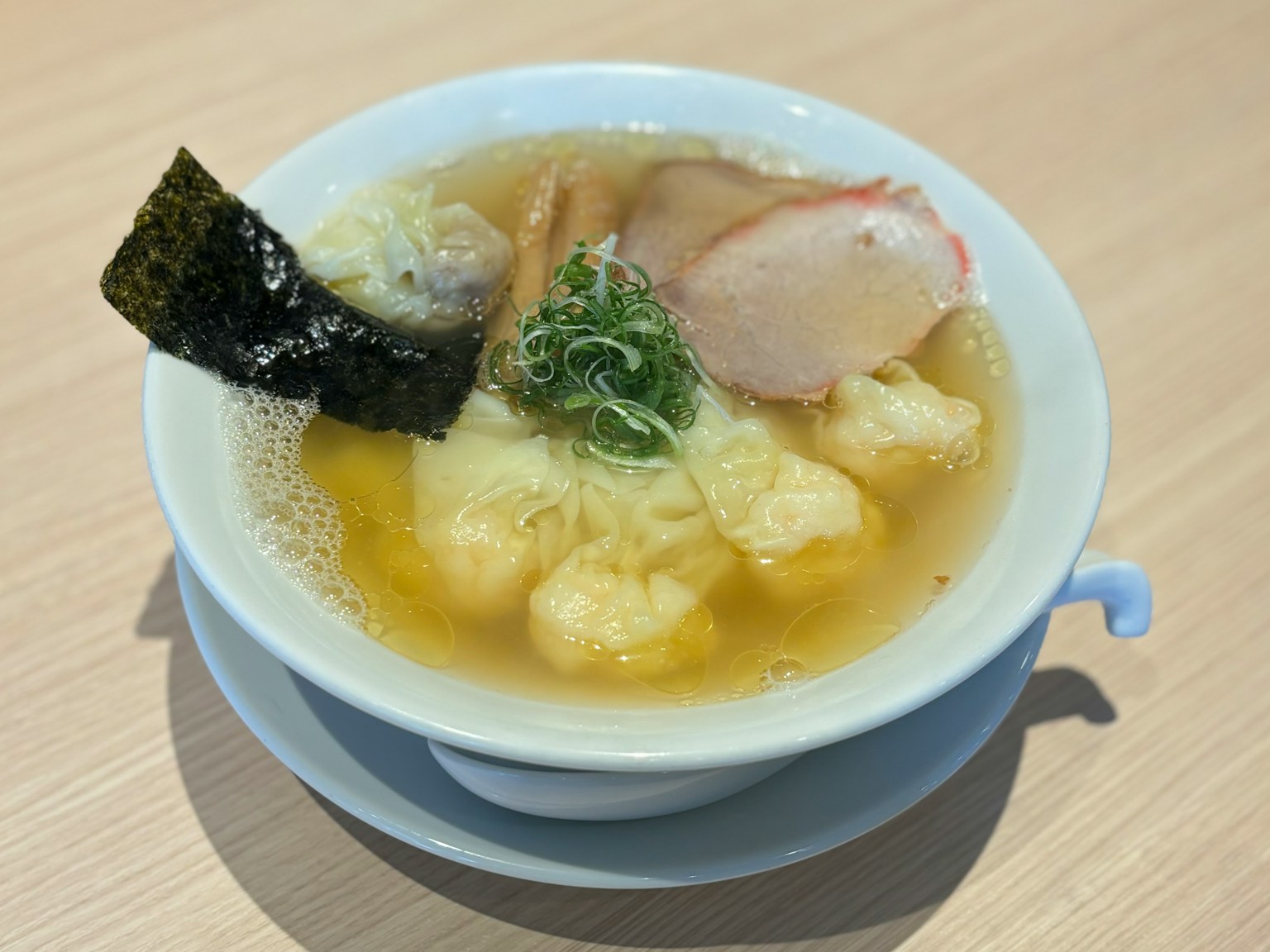 Bowl of soup ramen with sliced pork and seaweed topping clear broth