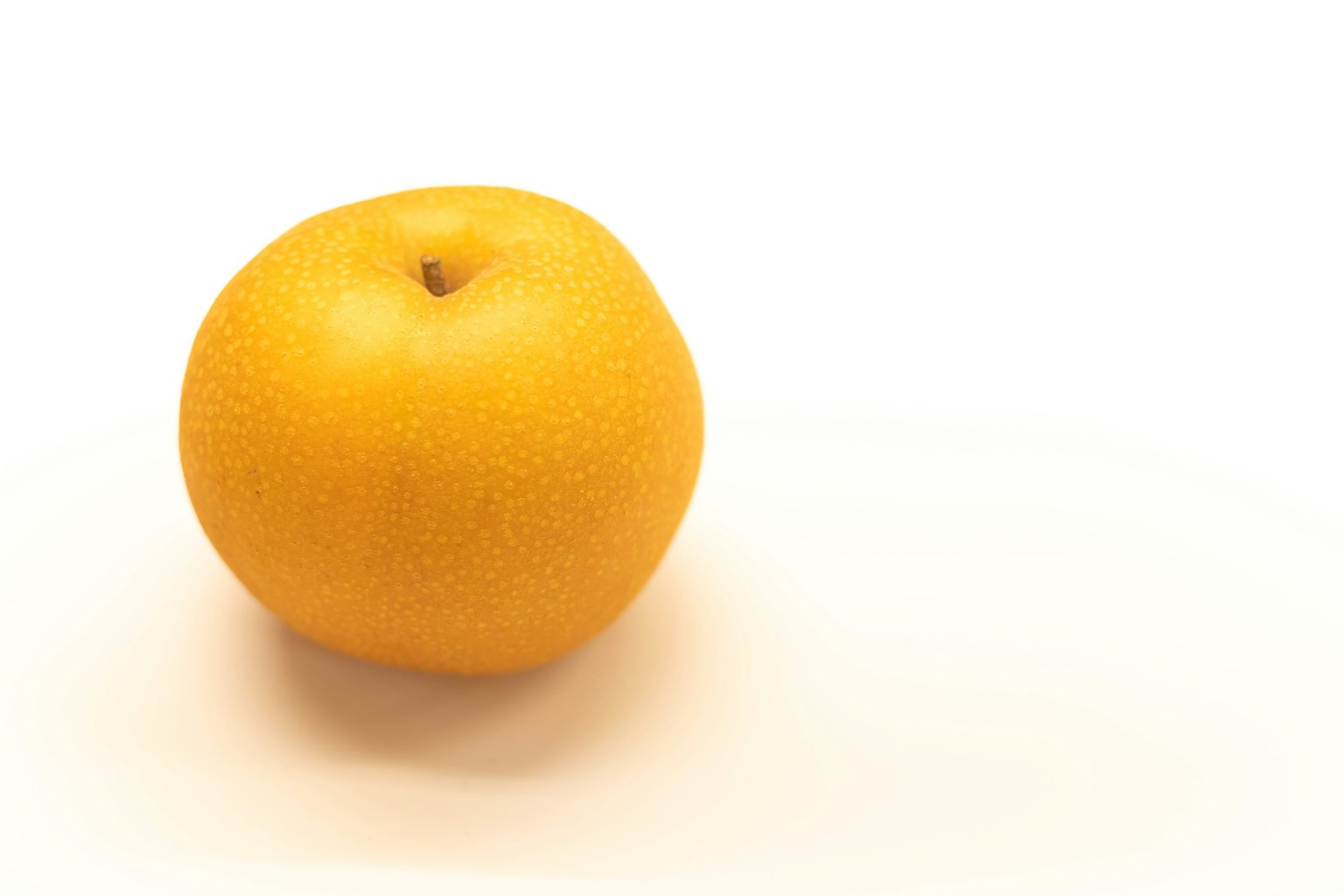 Une orange jaune vif reposant sur un fond blanc
