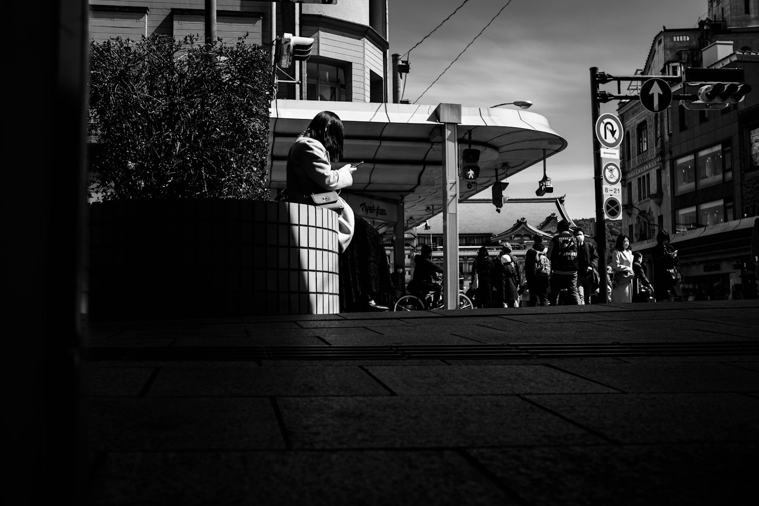 A person sitting on a bench in an urban landscape striking black and white contrast