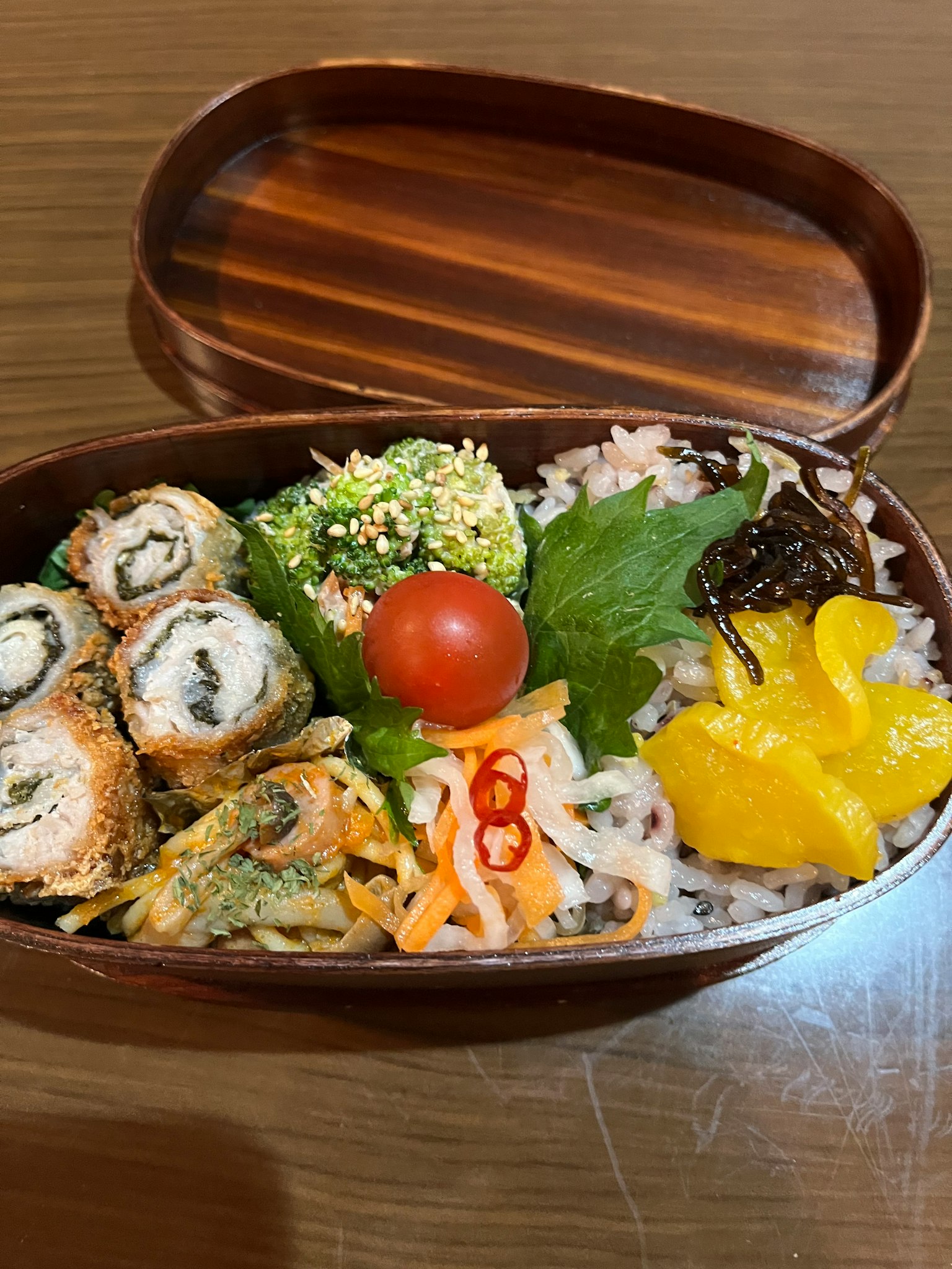 Eine Bento-Box gefüllt mit Sushi, Gemüse, Tomate und Obst