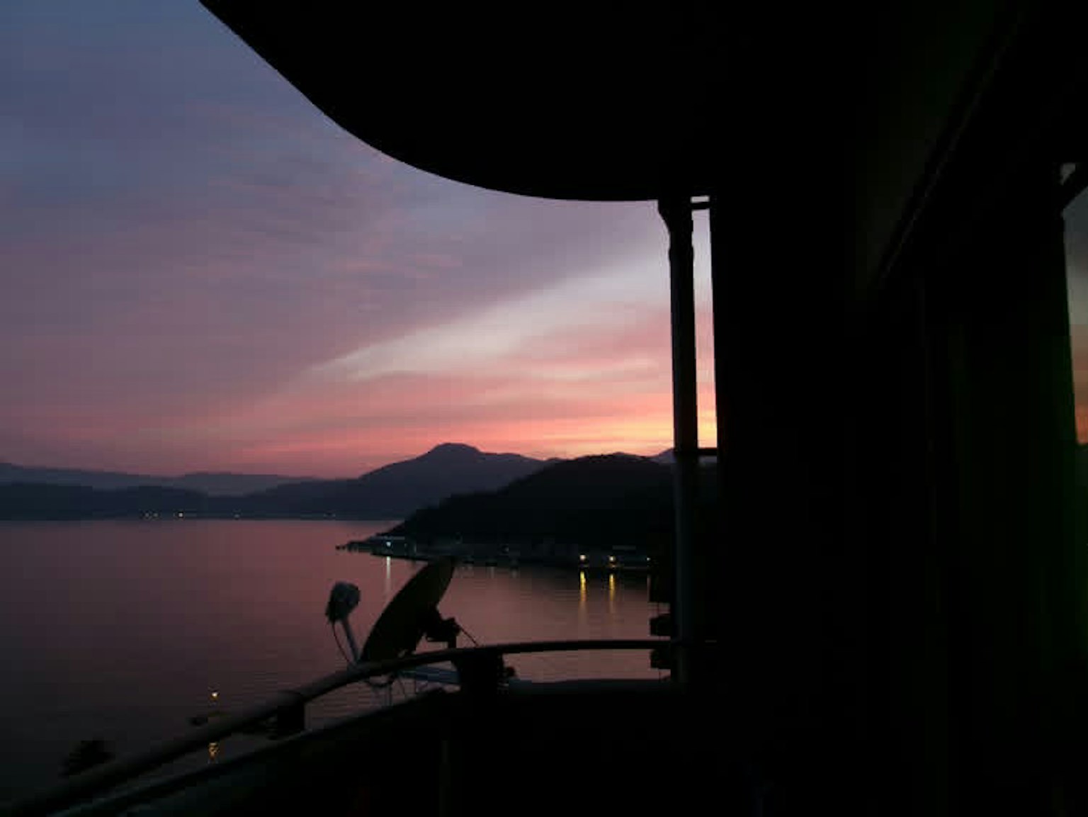 夕焼けの海の景色と山々のシルエットが見えるバルコニーからの眺め