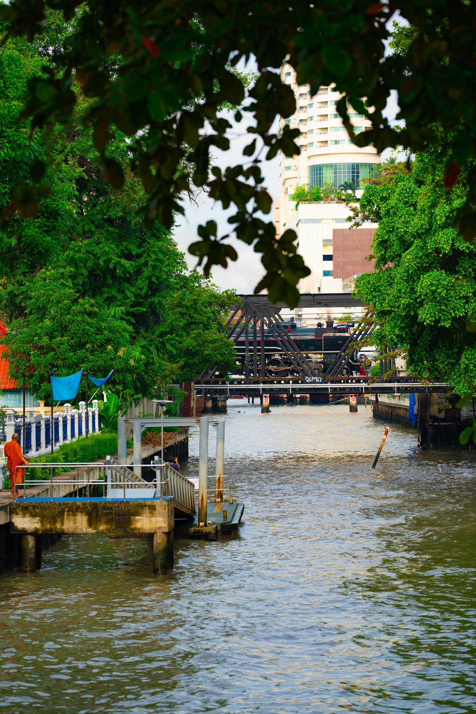 郁郁葱葱的绿树环绕的河流风景，建筑和人可见