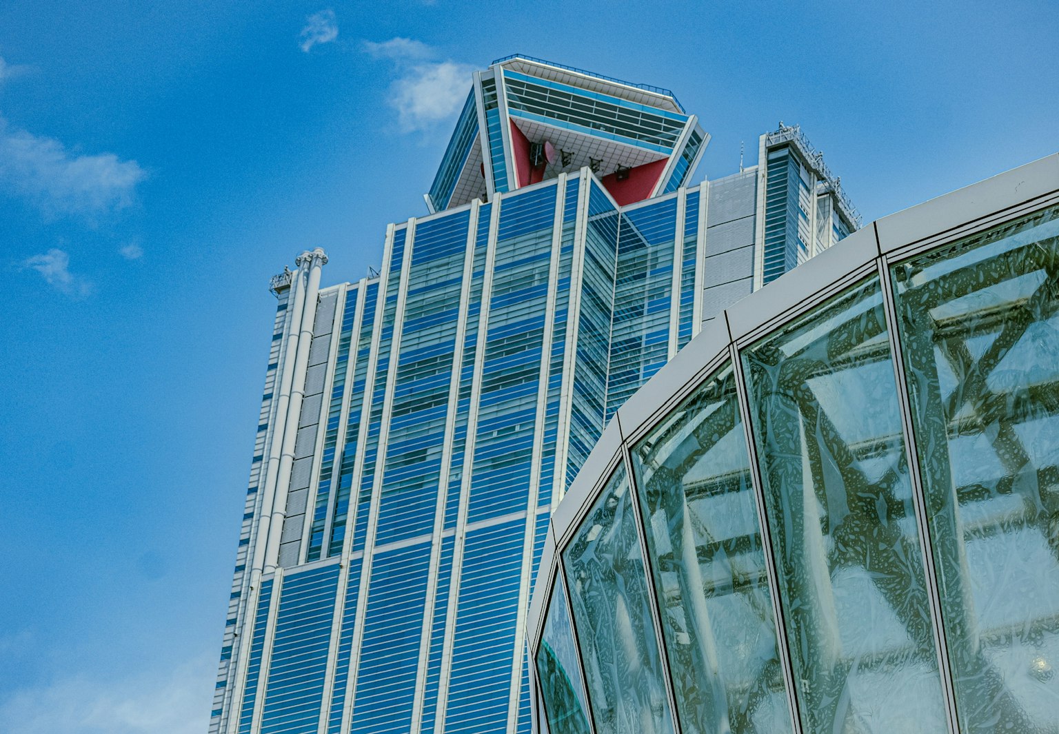 A modern skyscraper with a glass structure under a blue sky