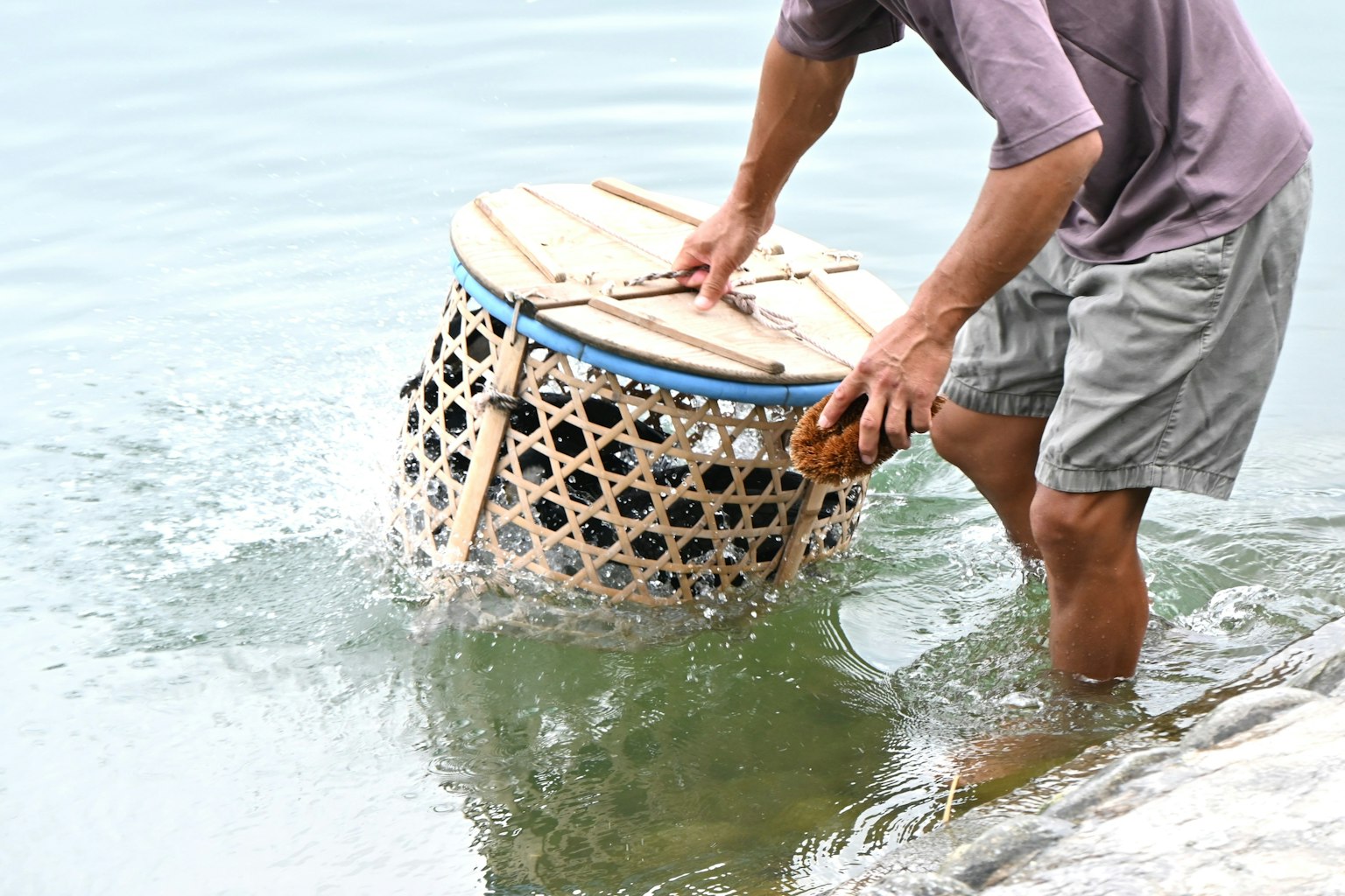 A man pulling a basket from the water
