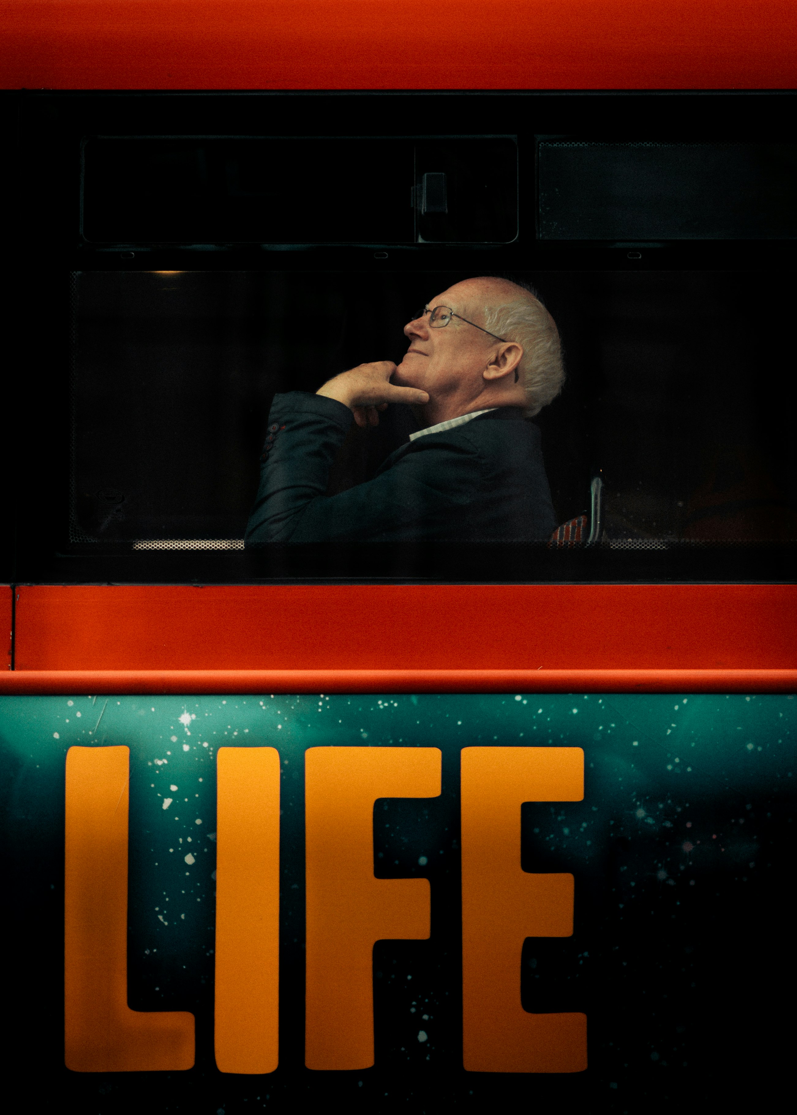 ชายคนหนึ่งมองเห็นได้ในห้องโดยสารรถที่มืด พร้อมคำว่า “LIFE” ใต้แสงสีแดง
