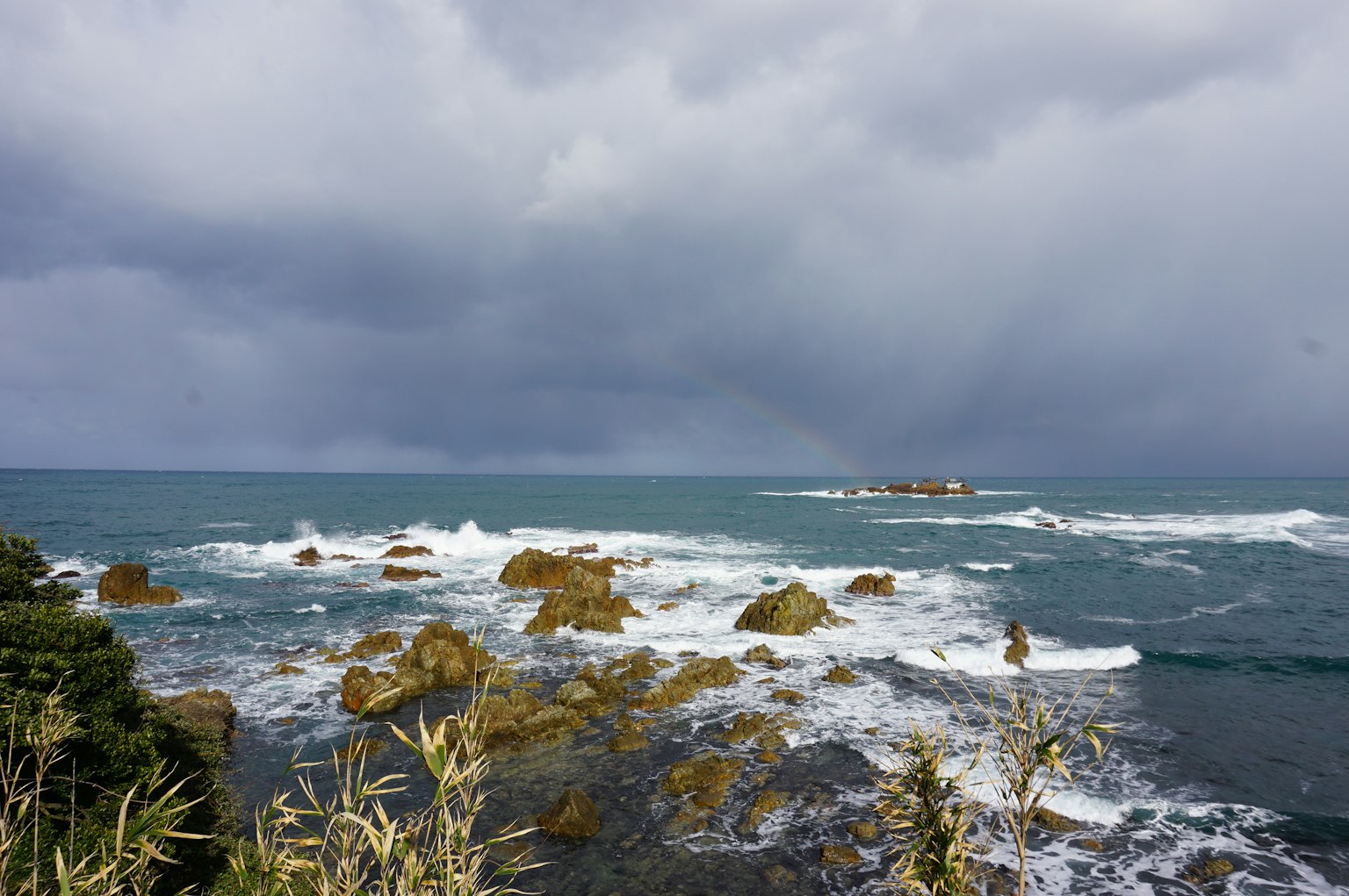 Rugged coastline with rocky formations under a cloudy sky and crashing waves