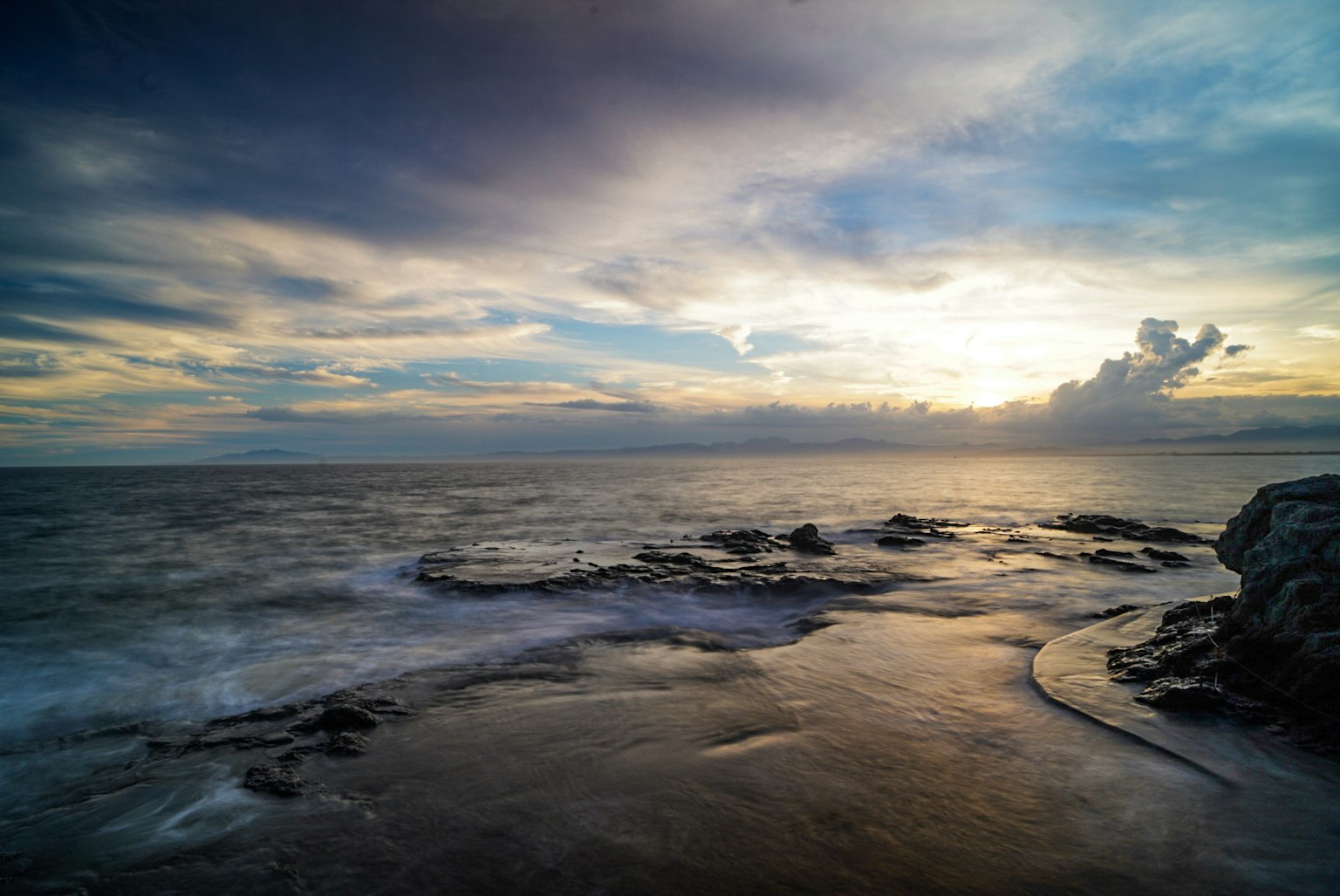 Vista panoramica dell'oceano al tramonto con nuvole e costa rocciosa