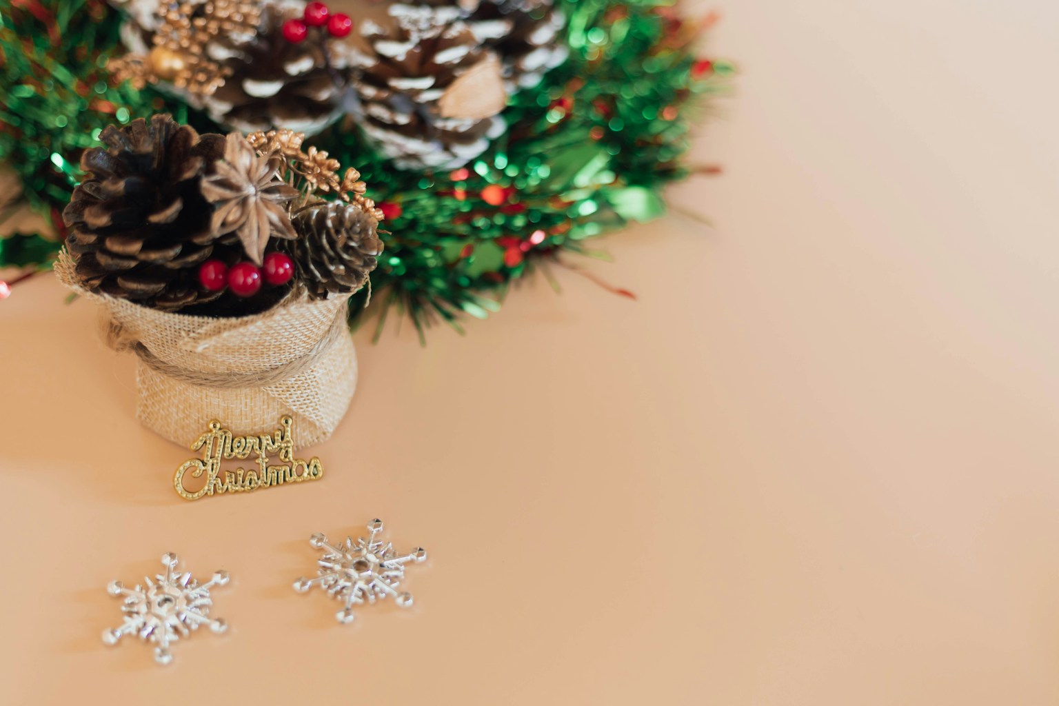 Tischszene mit Weihnachtsdekorationen wie Tannenzapfen und einem grünen Kranz