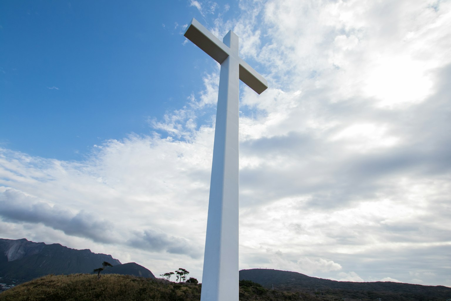 Une grande croix blanche sous un ciel bleu avec des nuages