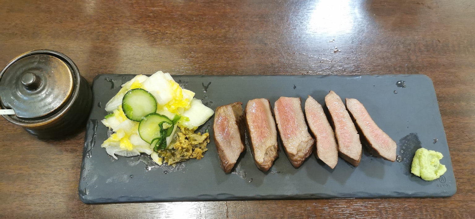 Thịt thái lát trên đĩa đen với salad và wasabi