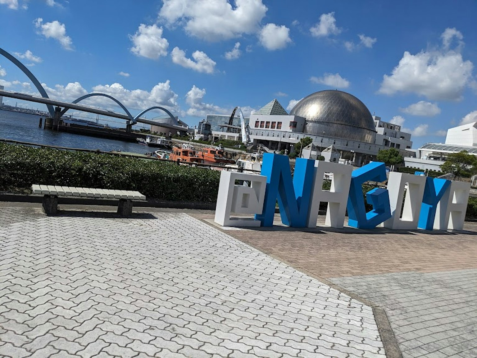 大型蓝色字母拼写‘NEW’与水边景观和现代建筑