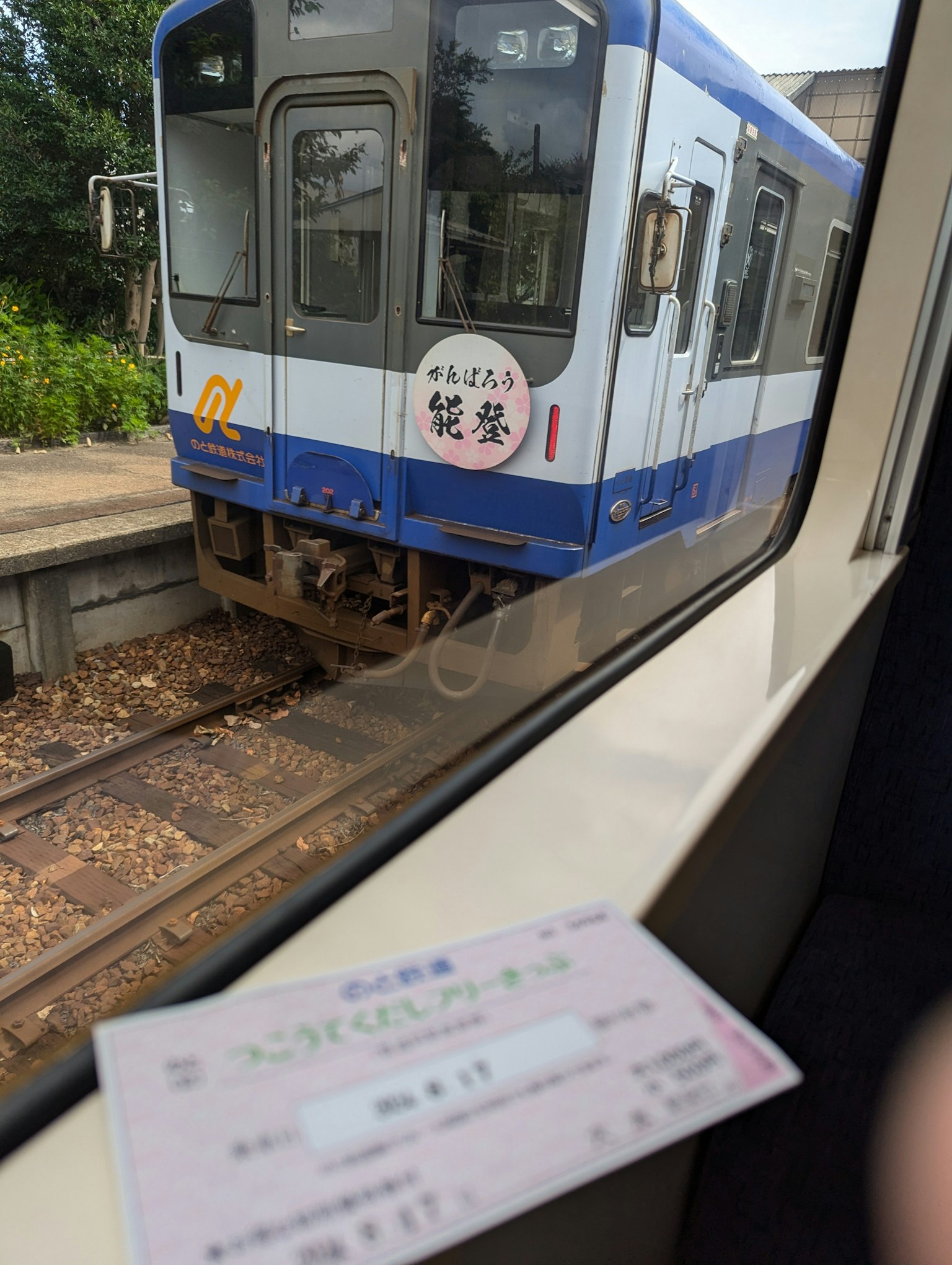 Blick auf einen blauen Zug vom Fenster mit einem Ticket