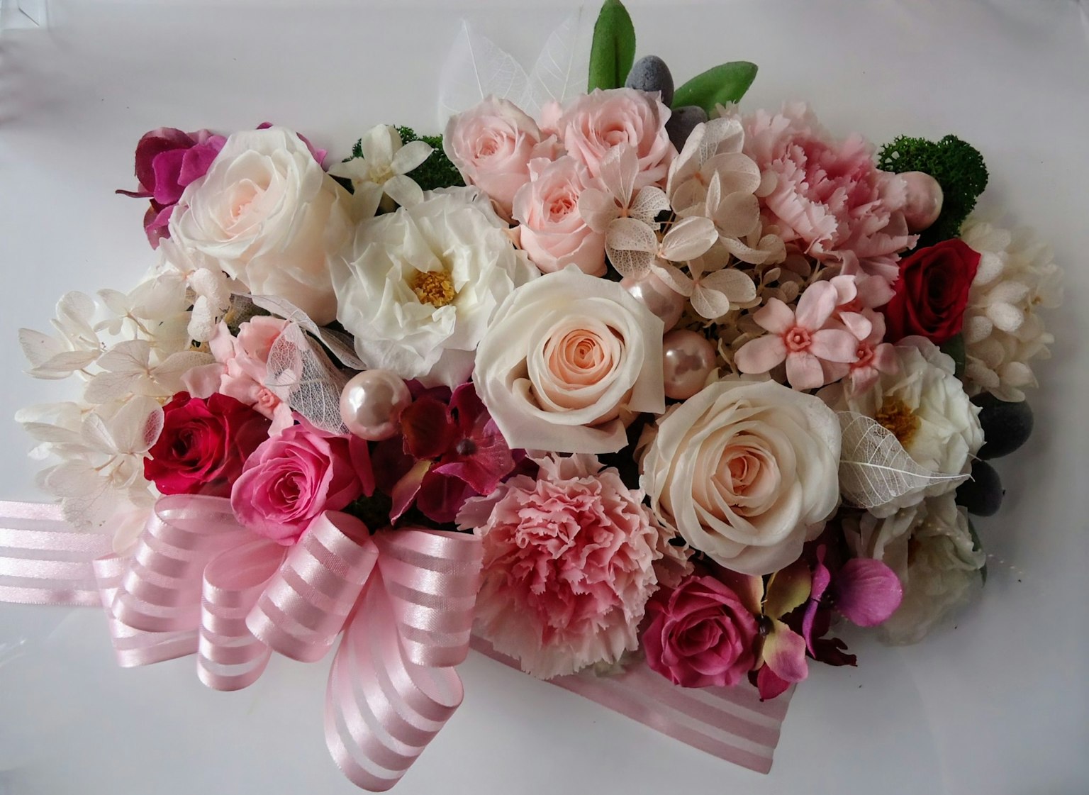 Ein wunderschönes Blumenarrangement mit einer Vielzahl von bunten Blumen und rosa Bändern