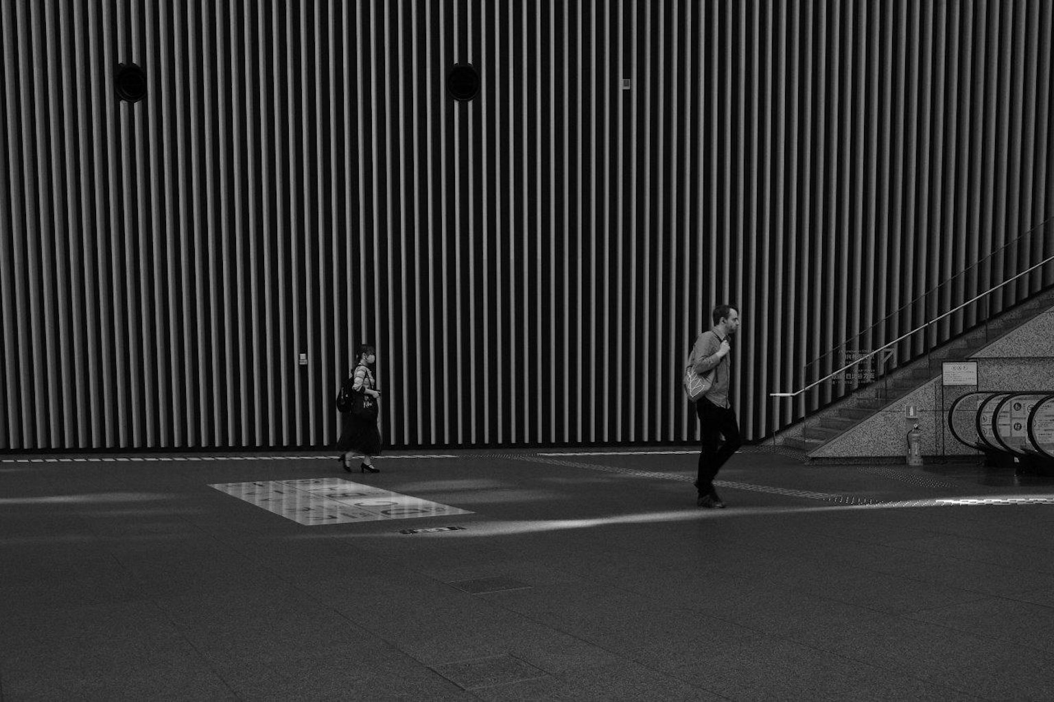 Escena urbana en blanco y negro con personas caminando apresuradamente