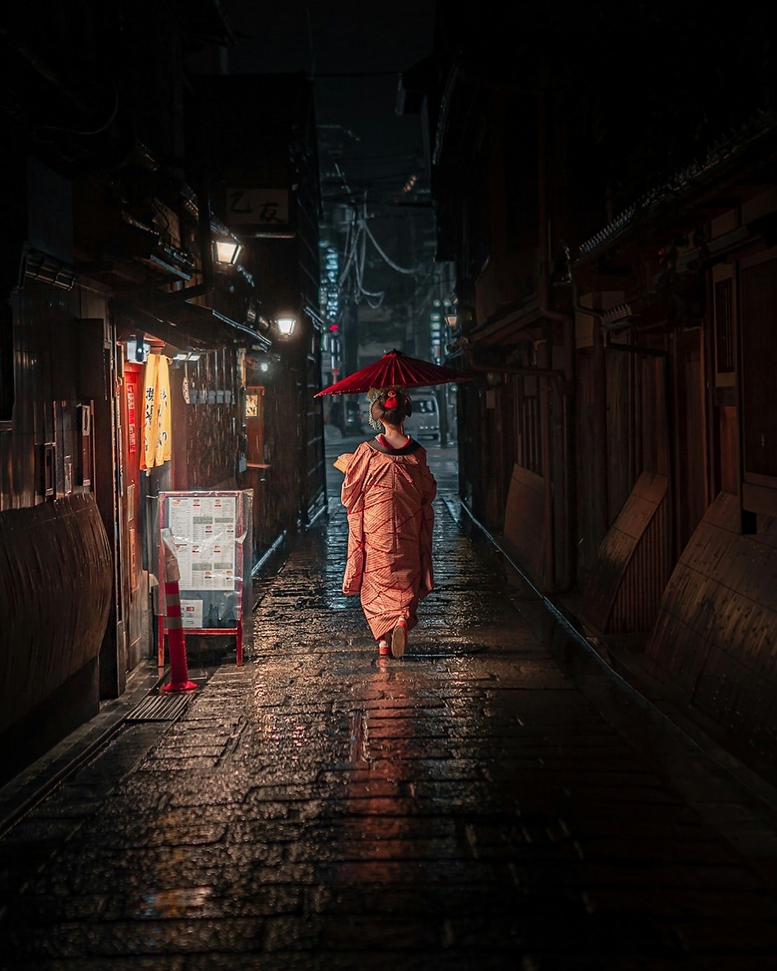 雨中小巷里撑着红色雨伞的人的背影