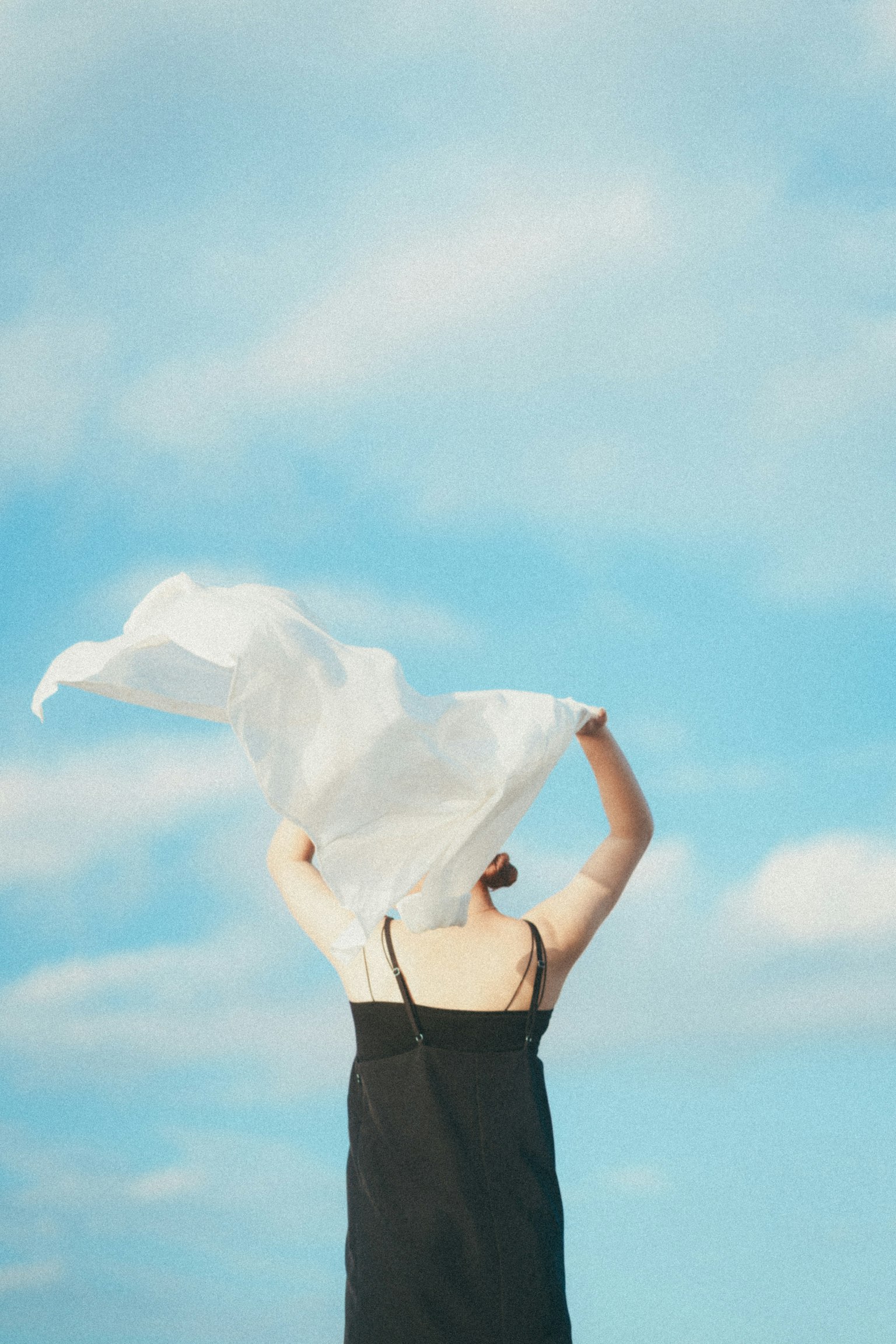 Mujer sosteniendo un paño blanco contra un cielo azul