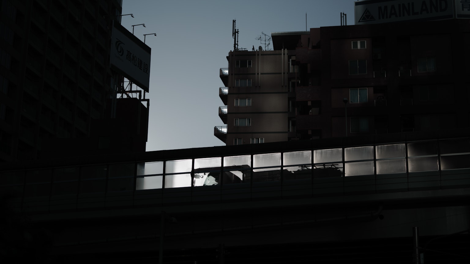Silhouette of high-rise buildings and shadow of a bridge in an urban landscape