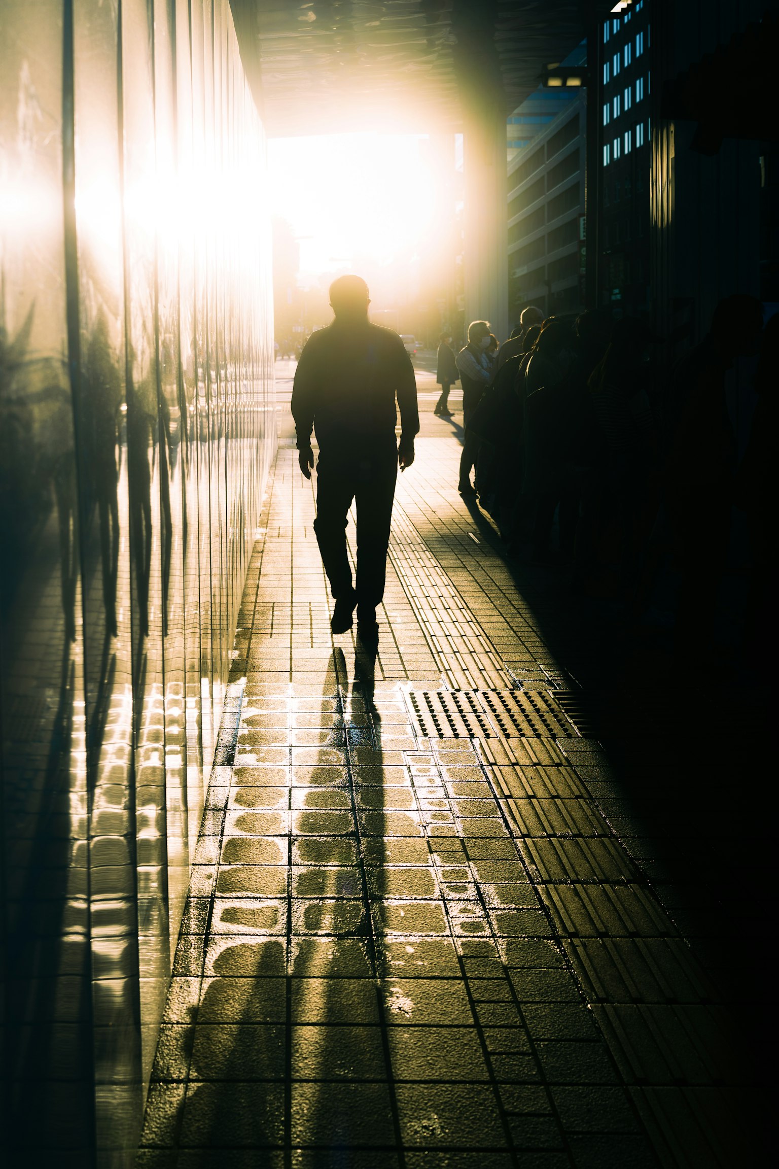 Silhouette orang berjalan menuju cahaya terang di lingkungan perkotaan