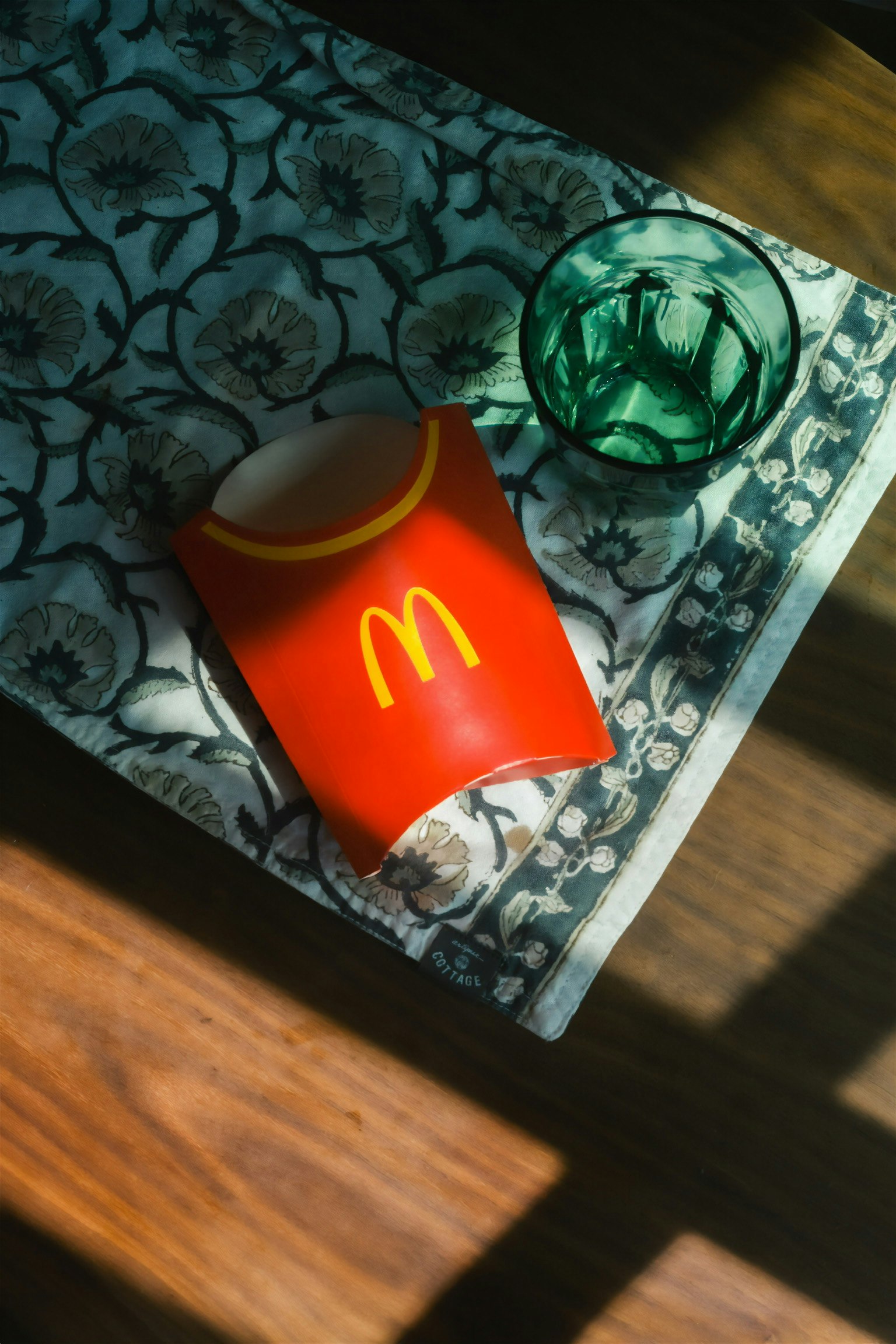 Escena interior con una bolsa roja de McDonald’s y un objeto verde sobre una alfombra con estampado