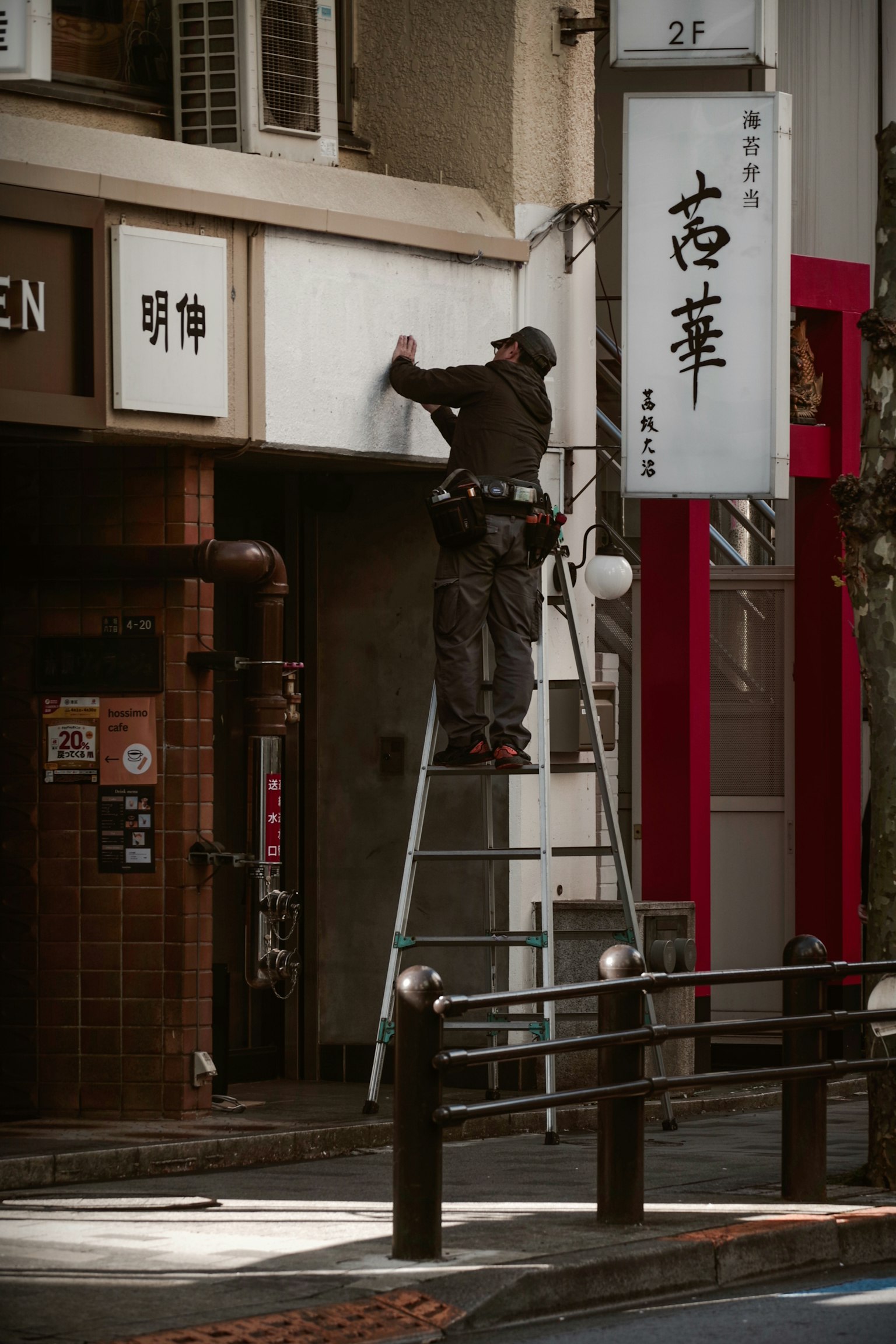 사다리에 서서 간판을 수리하는 작업자