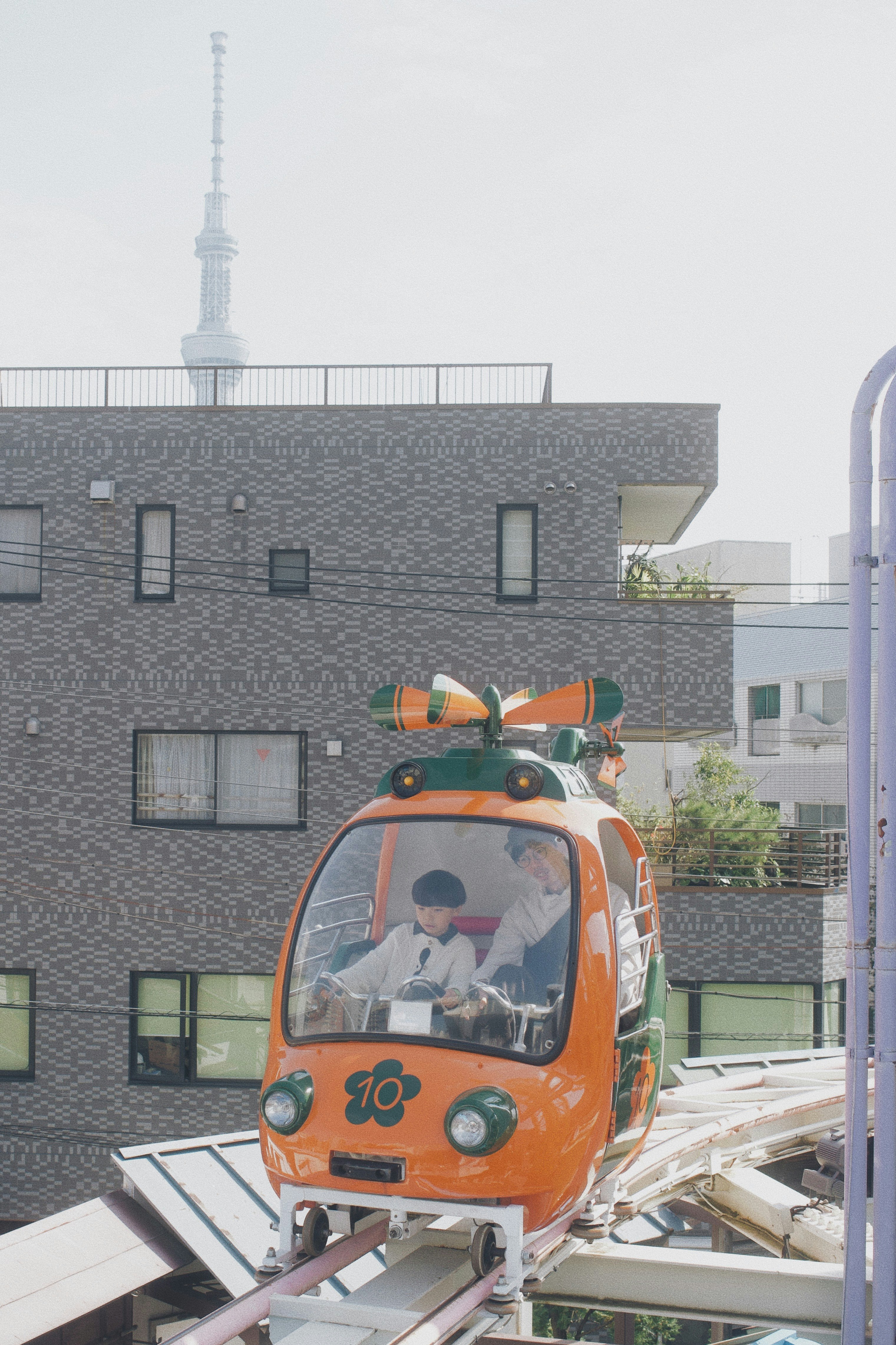 屋上のオレンジ色の小型車両と東京スカイツリーを望む風景