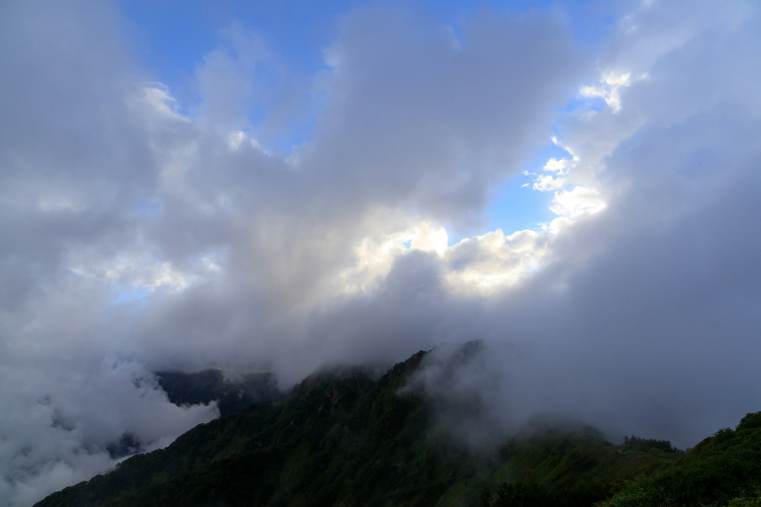 Montagne avvolte dalle nuvole con uno scorcio di cielo blu