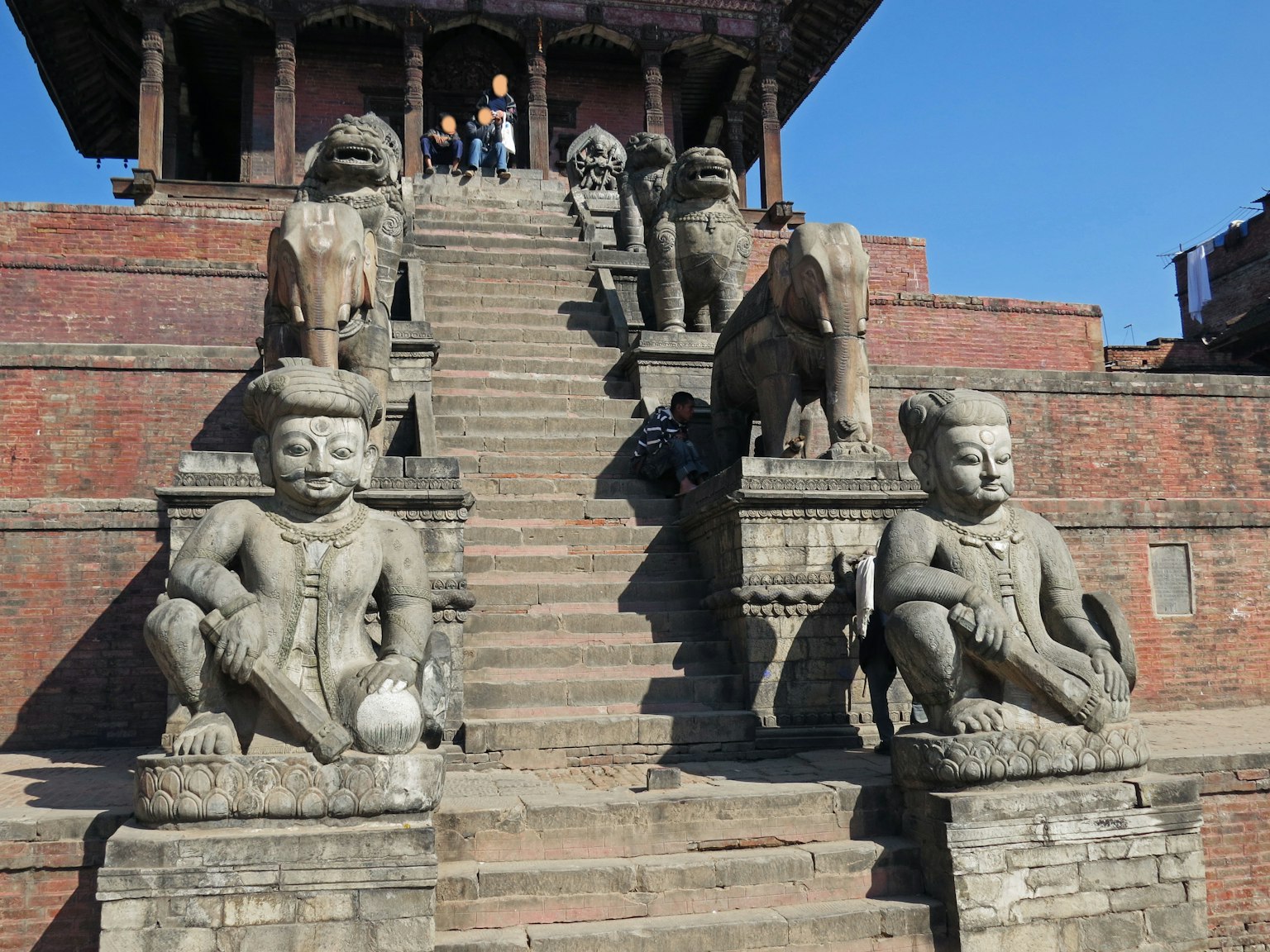 Statues en pierre de chaque côté d'un escalier menant à un temple