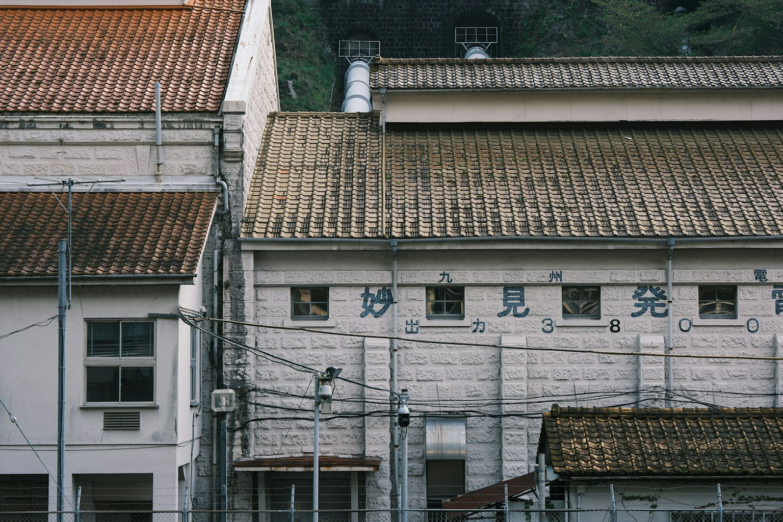 Cảnh bên ngoài của một tòa nhà cũ với mái rỉ sét và hàng rào