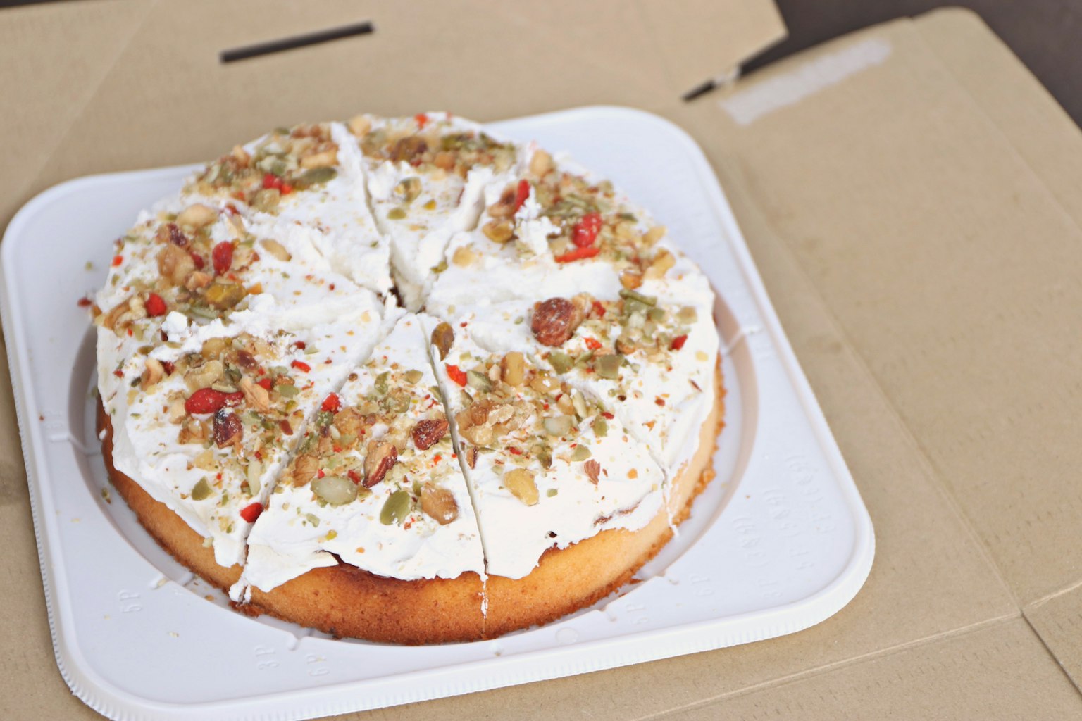 Ein mit Sahne und Nüssen dekorierter Kuchen in einer Pappschachtel präsentiert