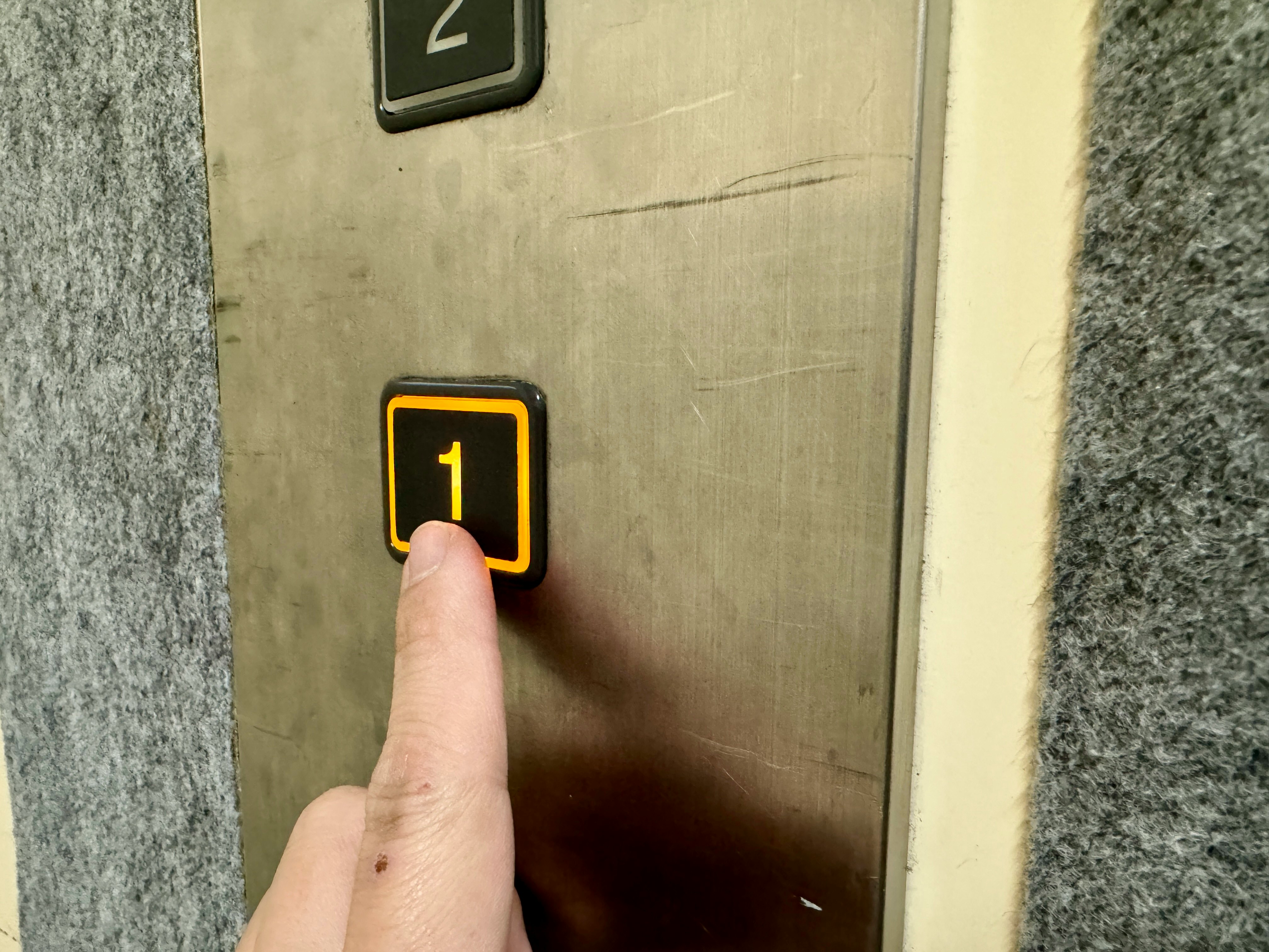 Nahaufnahme eines Fingers, der den Aufzug-1-Knopf drückt