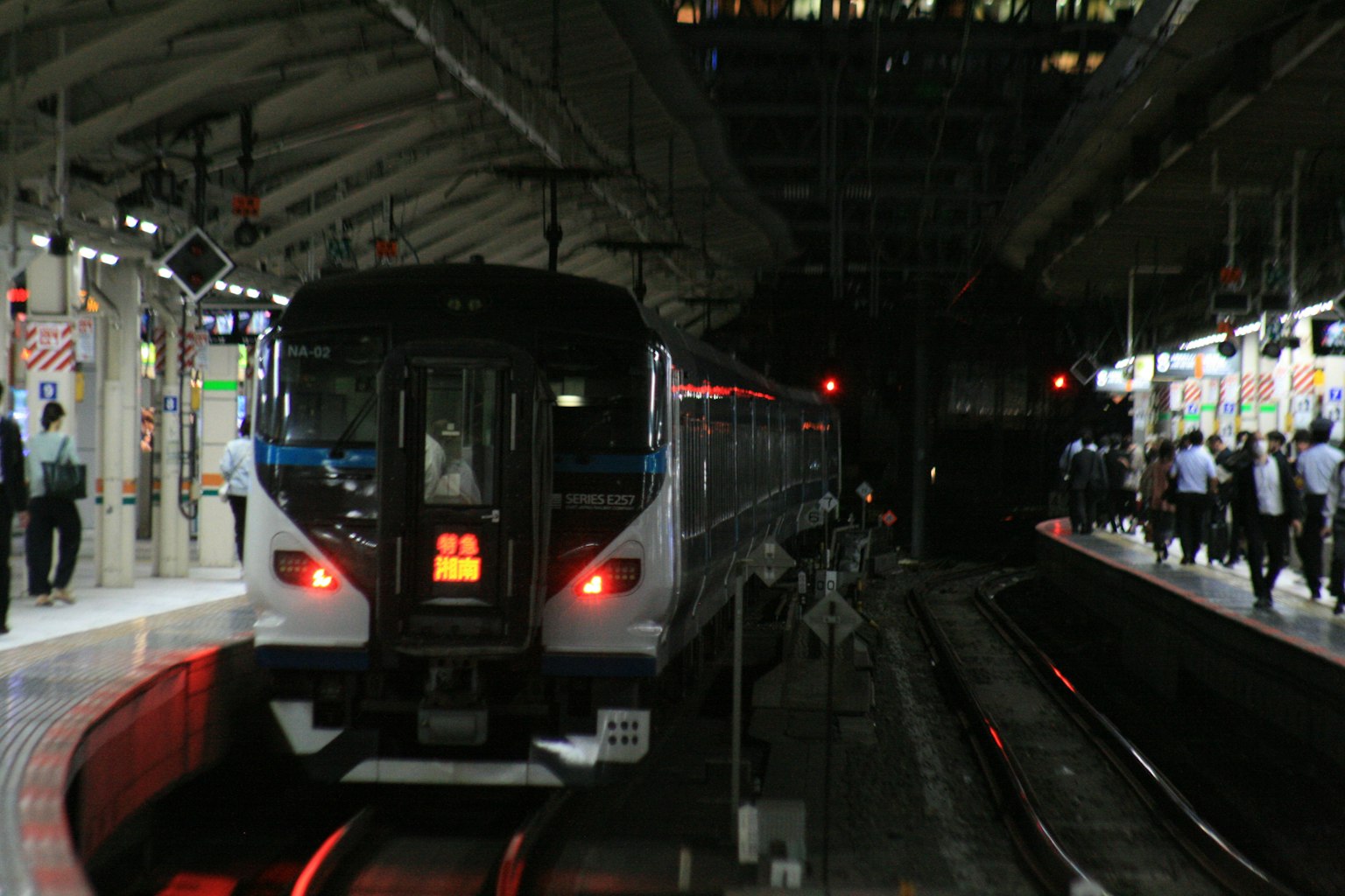 Kereta berhenti di stasiun malam dengan penumpang di peron