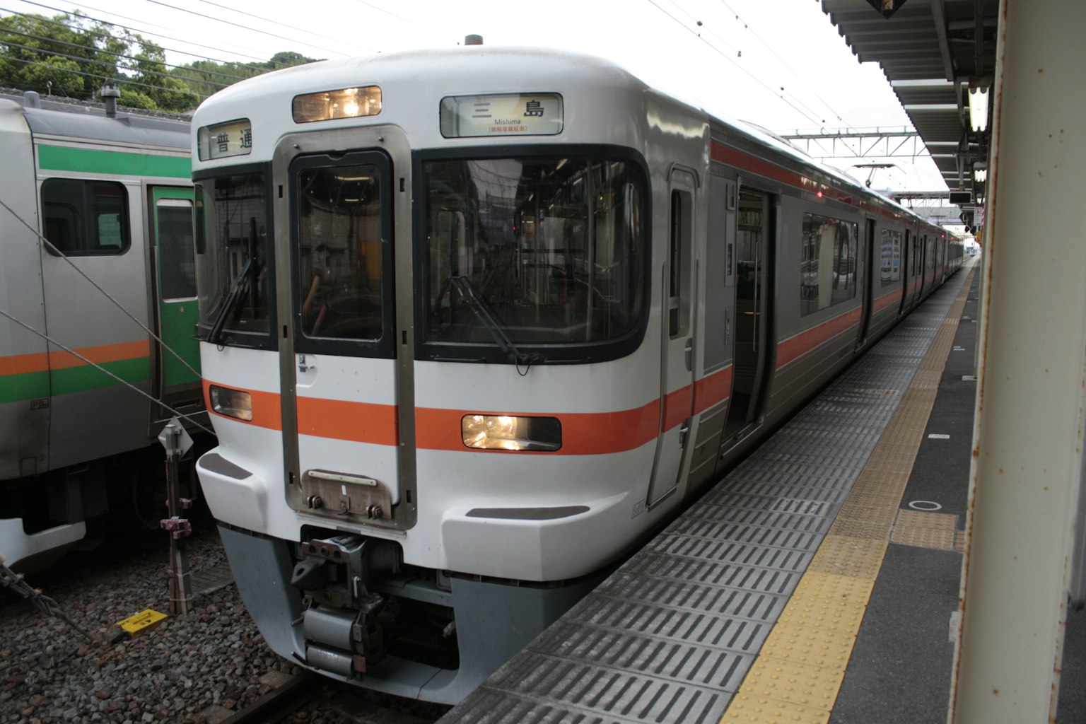現代火車停靠在車站，具有白色和橙色條紋