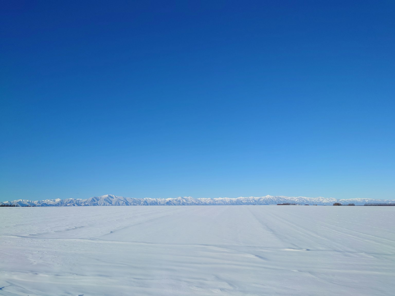 Weite schneebedeckte Landschaft unter klarem blauen Himmel