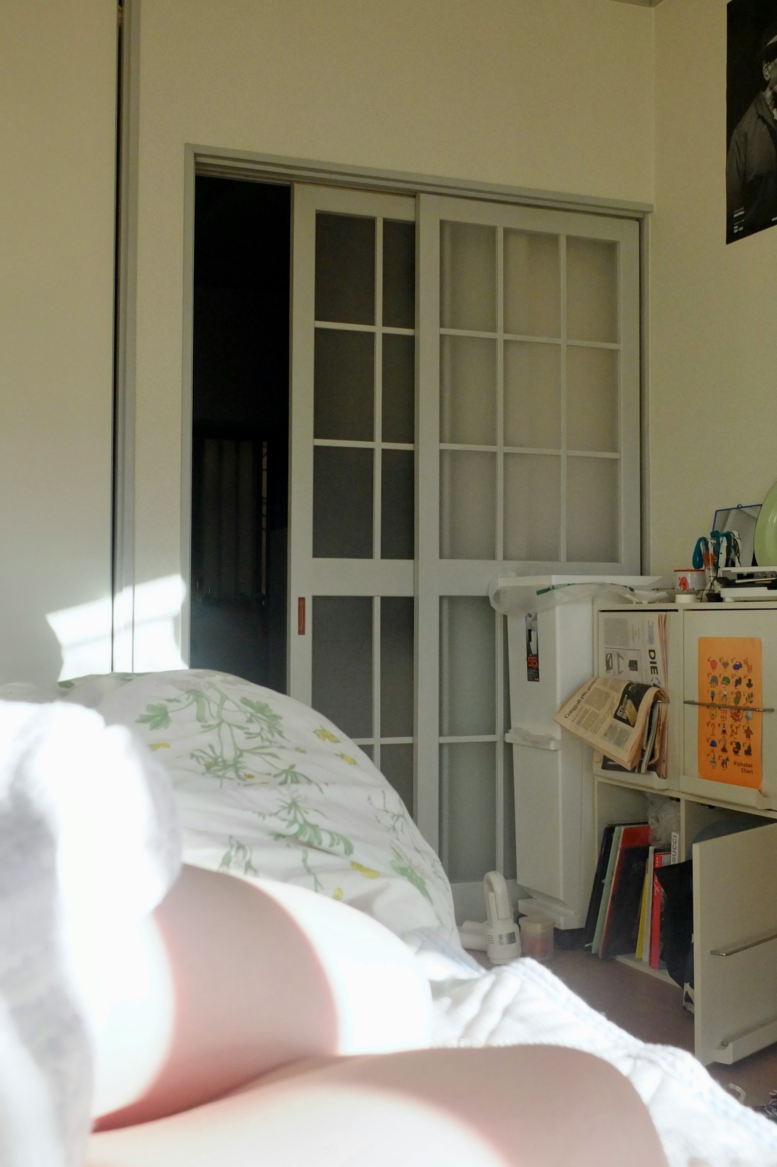 Interior view of a room from a bed white curtains and wooden sliding doors natural light streaming in