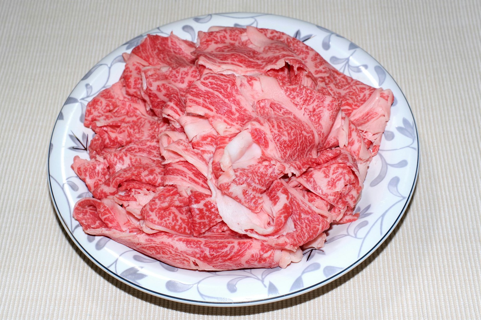 Daging wagyu tipis disusun di piring putih