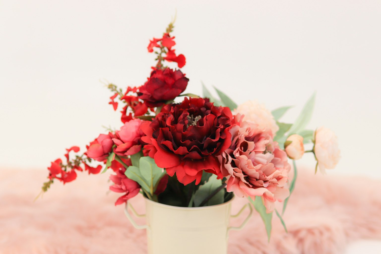 Strauß aus roten und rosa Blumen in einer weißen Vase