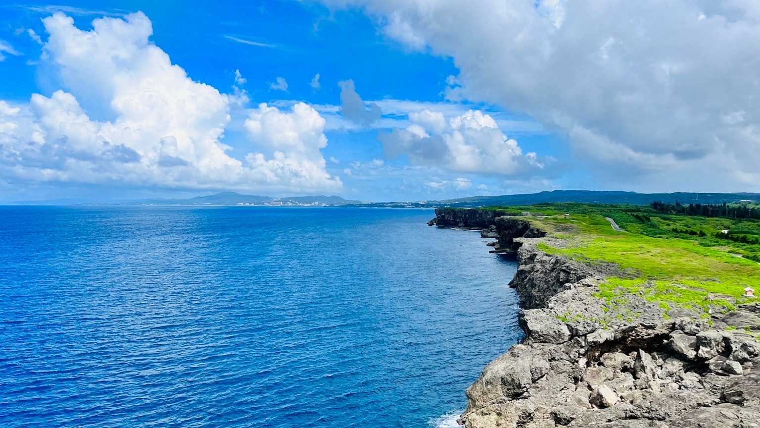 Schöne Aussicht auf den blauen Ozean und weiße Wolken grüne Wiesen und felsige Klippen