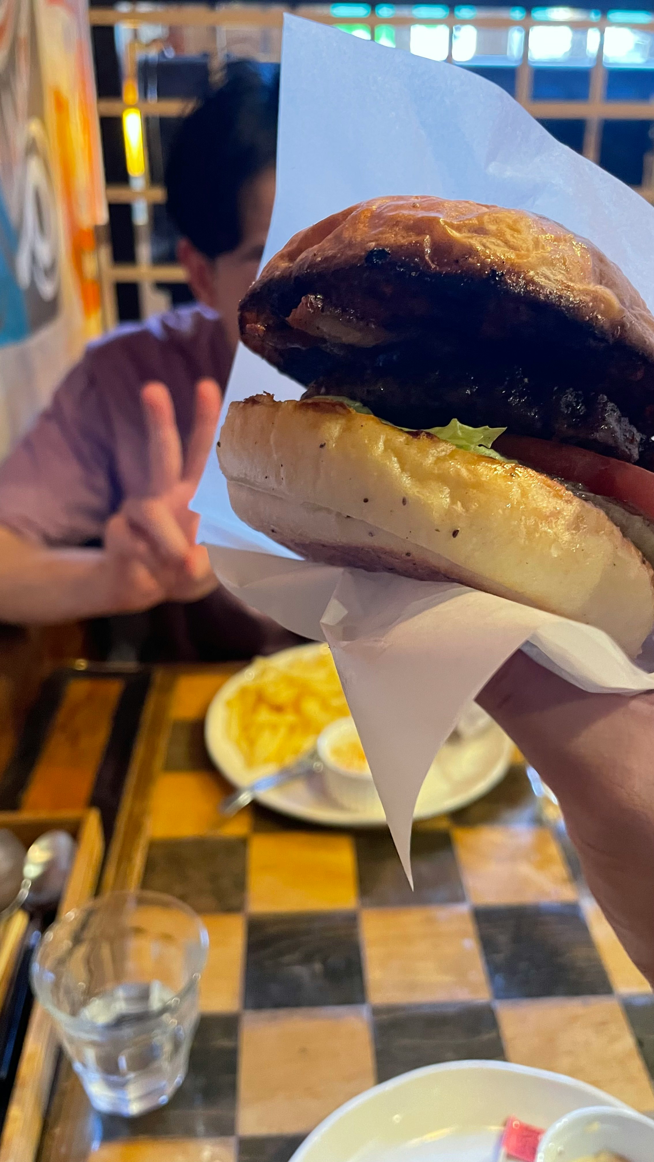 paper-wrapped burger on a restaurant table with fries