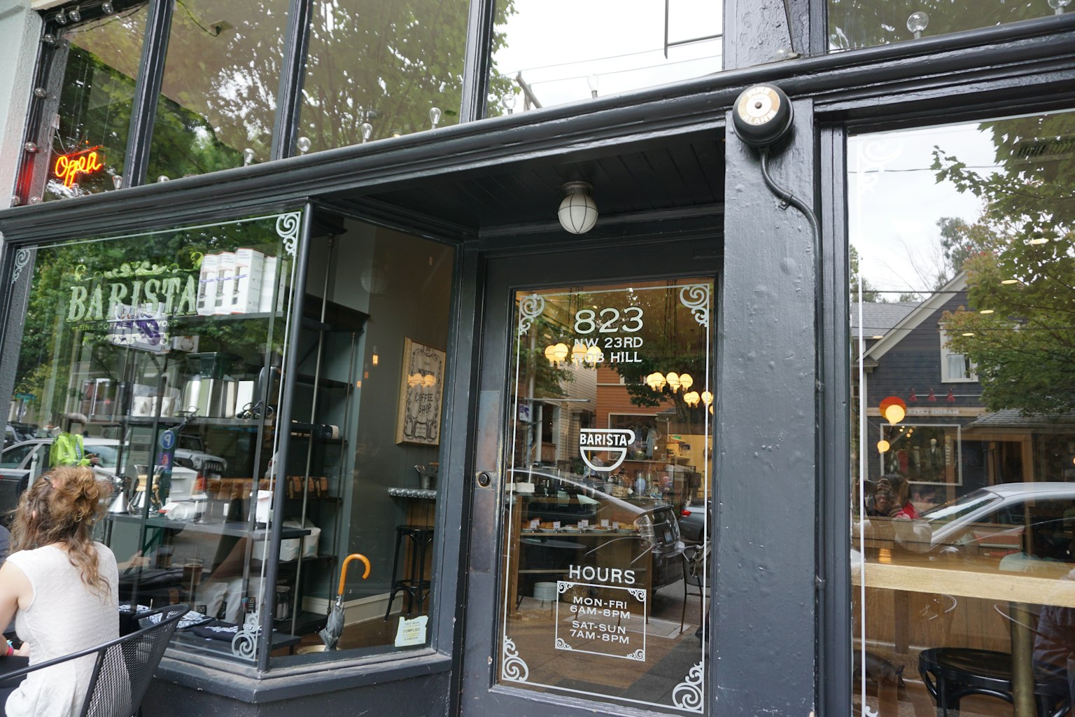 Entrée de café avec porte en verre affichant le nom et les horaires d'ouverture