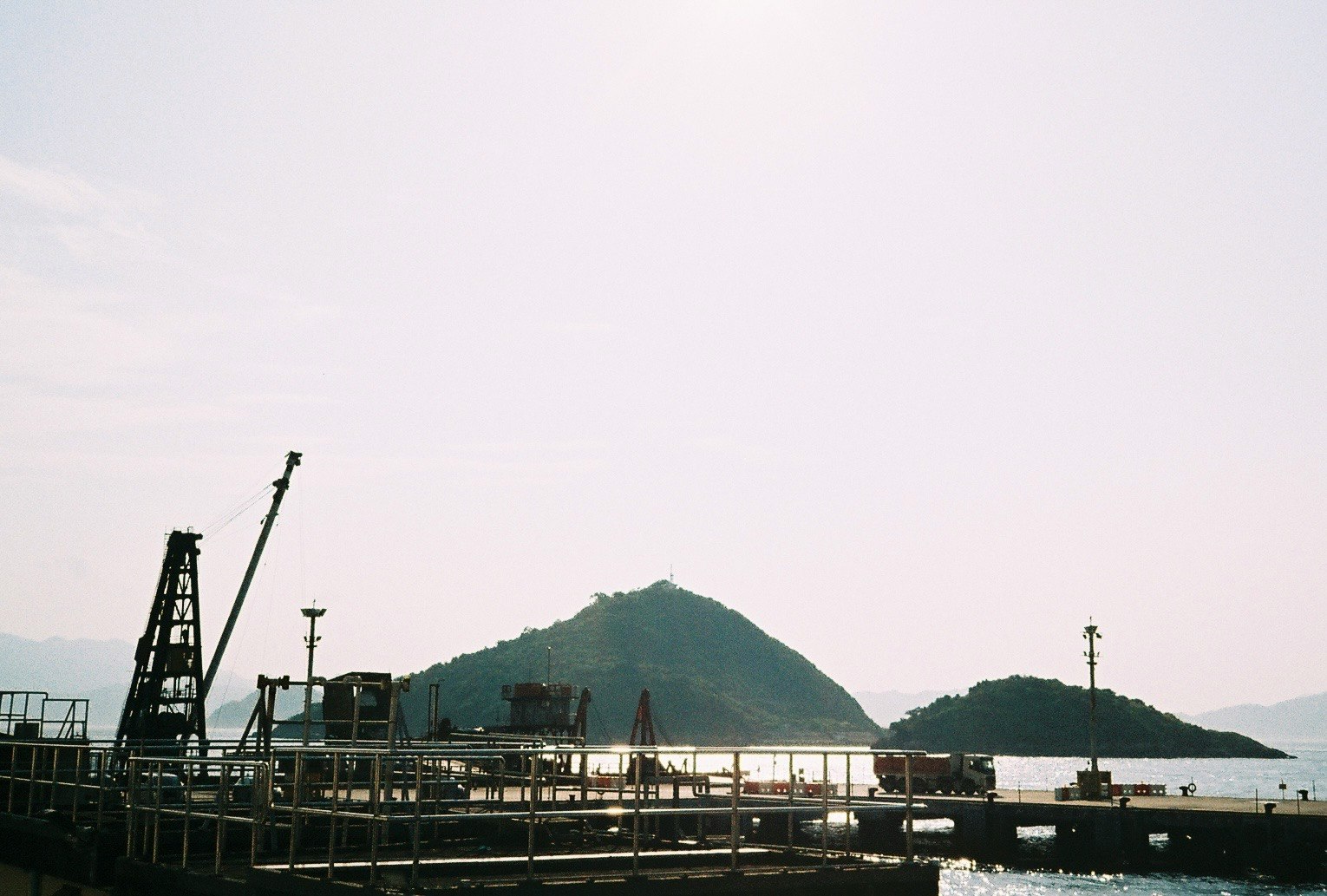 港の岸壁とクレーン、遠くに山が見える風景