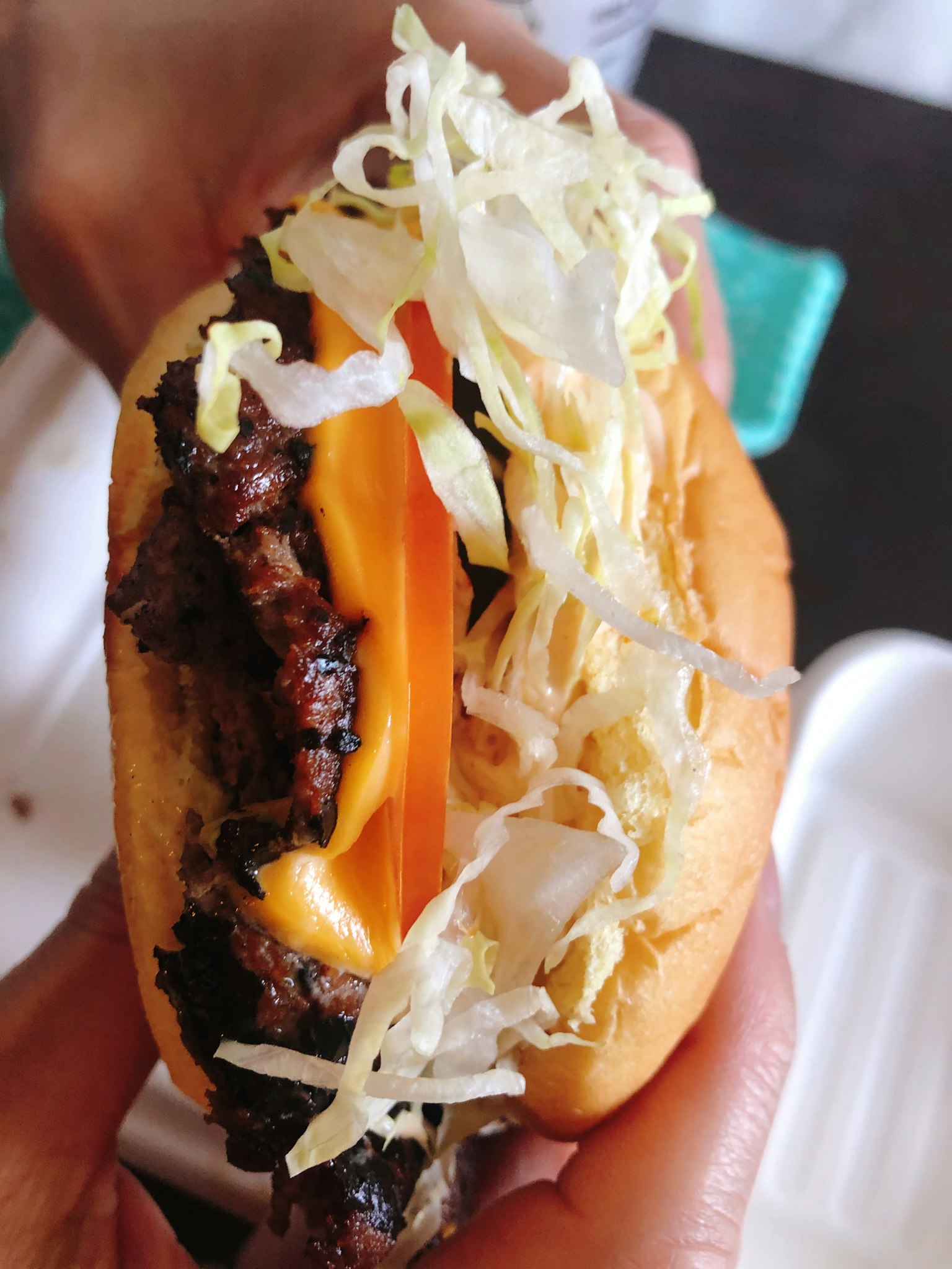 Primer plano de una hamburguesa con queso derretido y lechuga picada