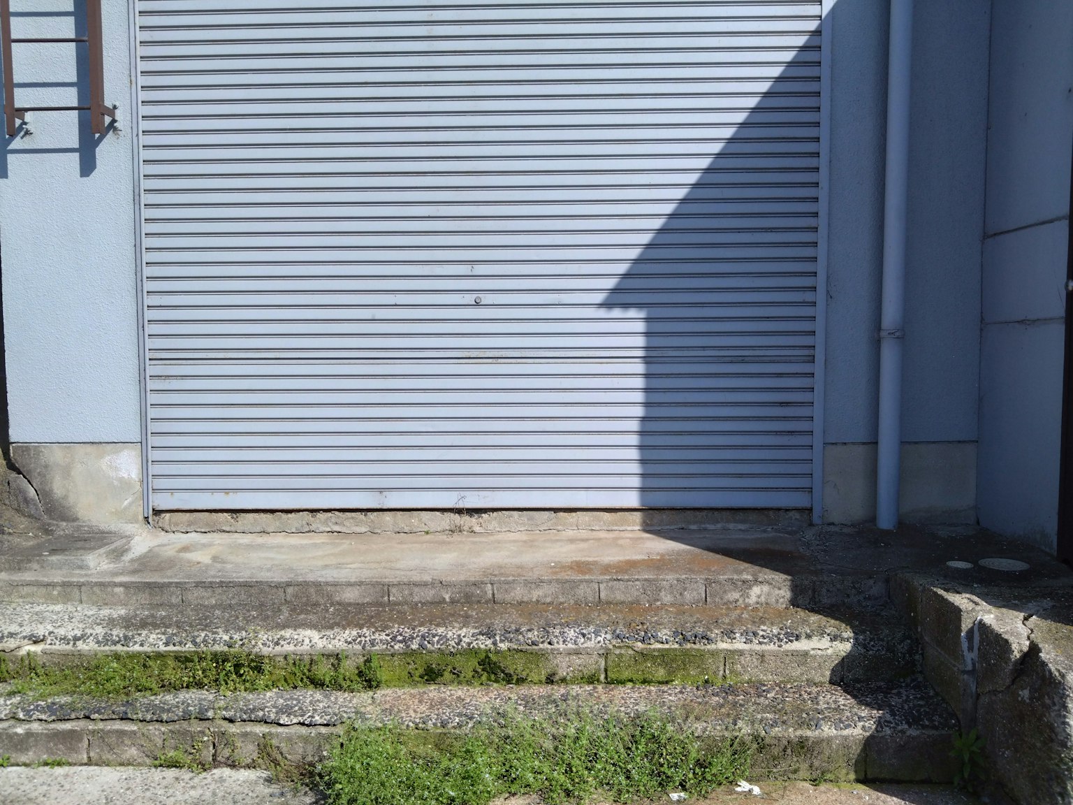 Immagine di una serranda blu e gradini in cemento