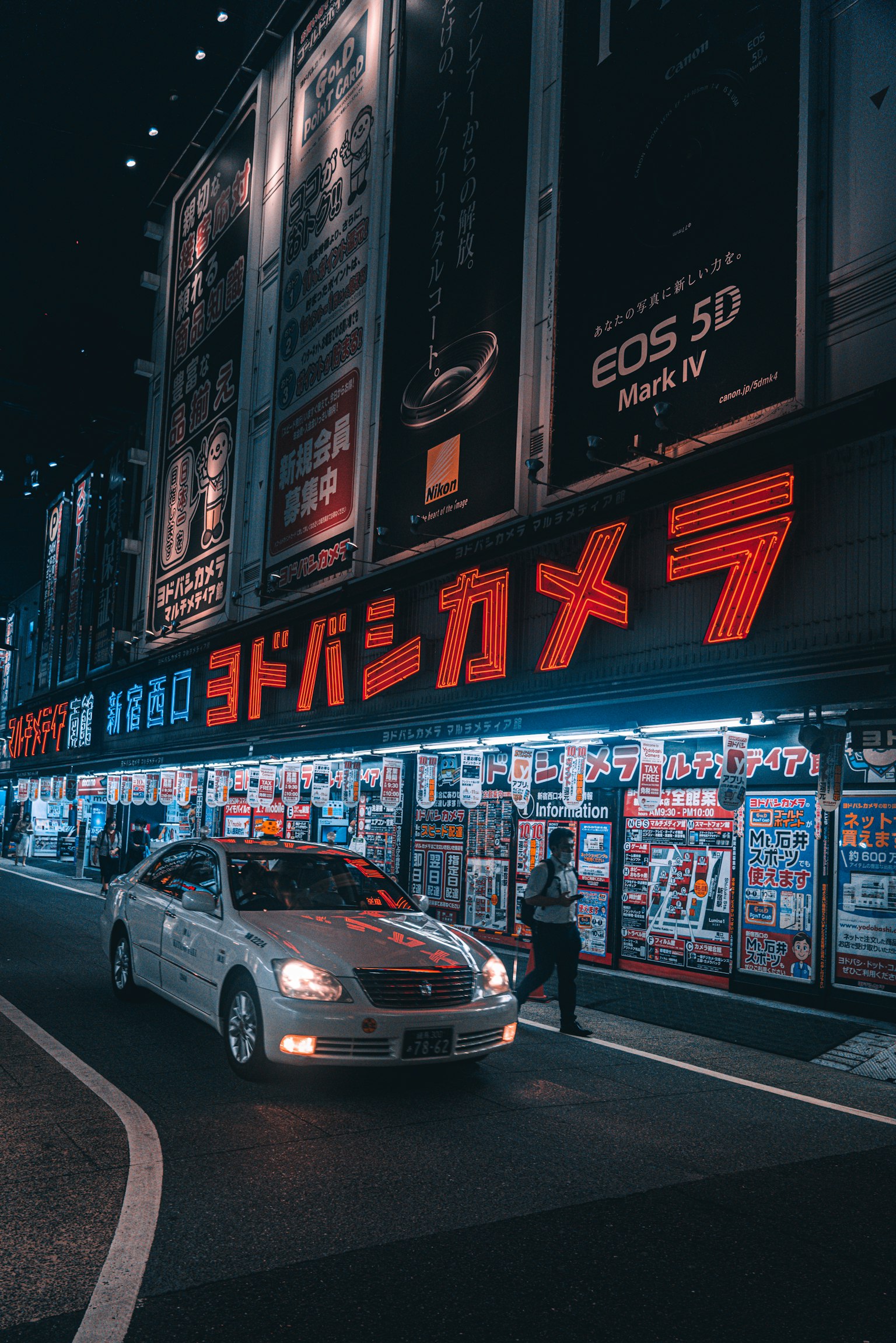 夜景中的友都八喜相机招牌和出租车