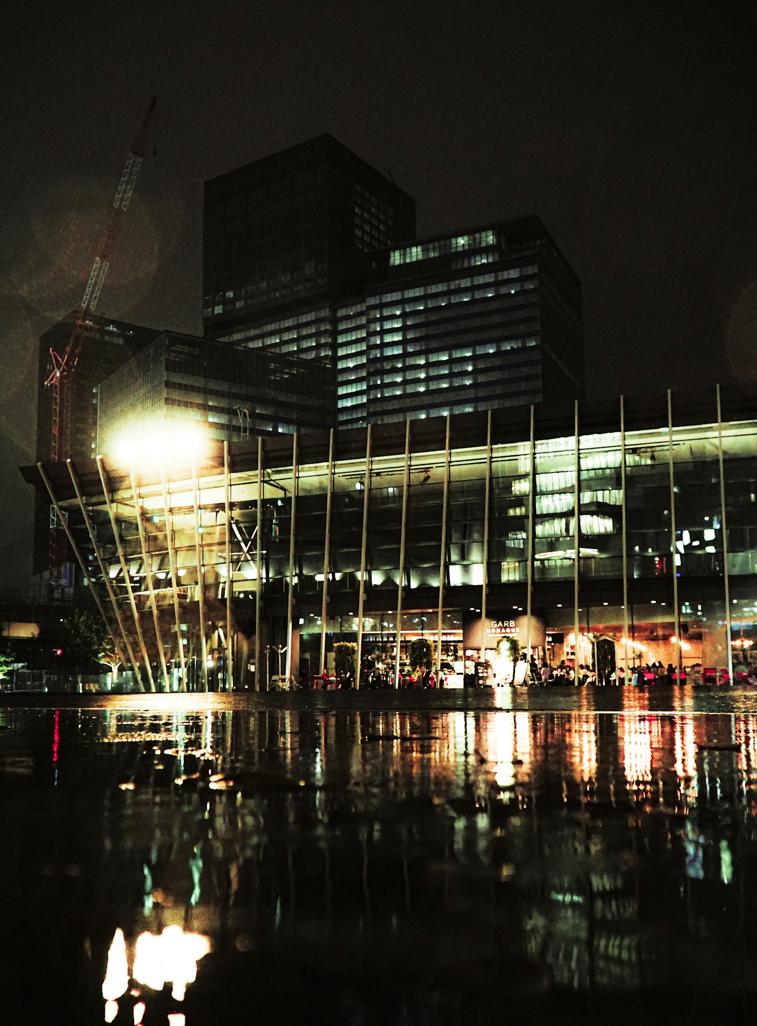 Edificio moderno che si riflette nell'acqua di notte con skyline urbano