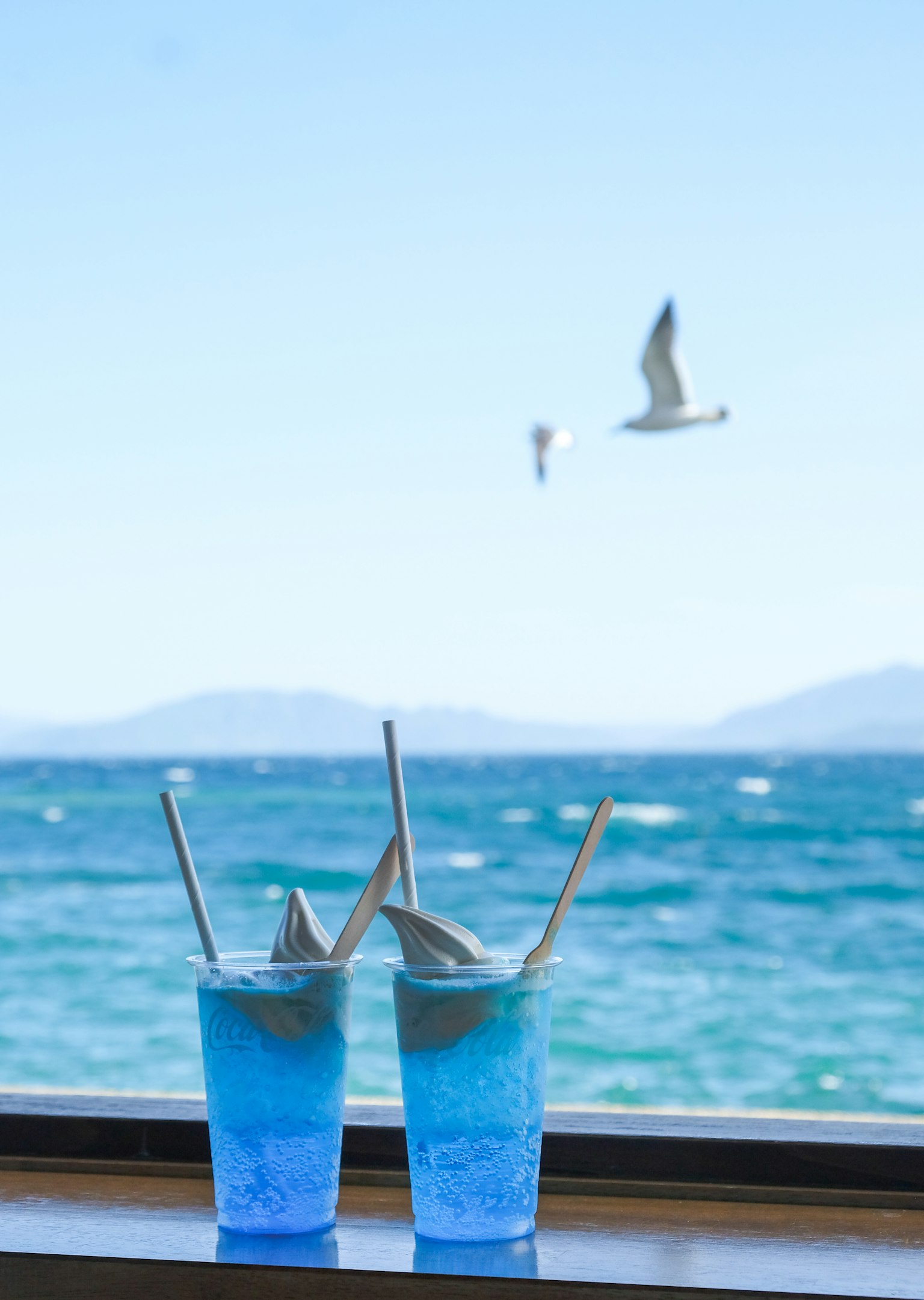Zwei blaue Cocktails auf einer Fensterbank mit Blick auf den Ozean