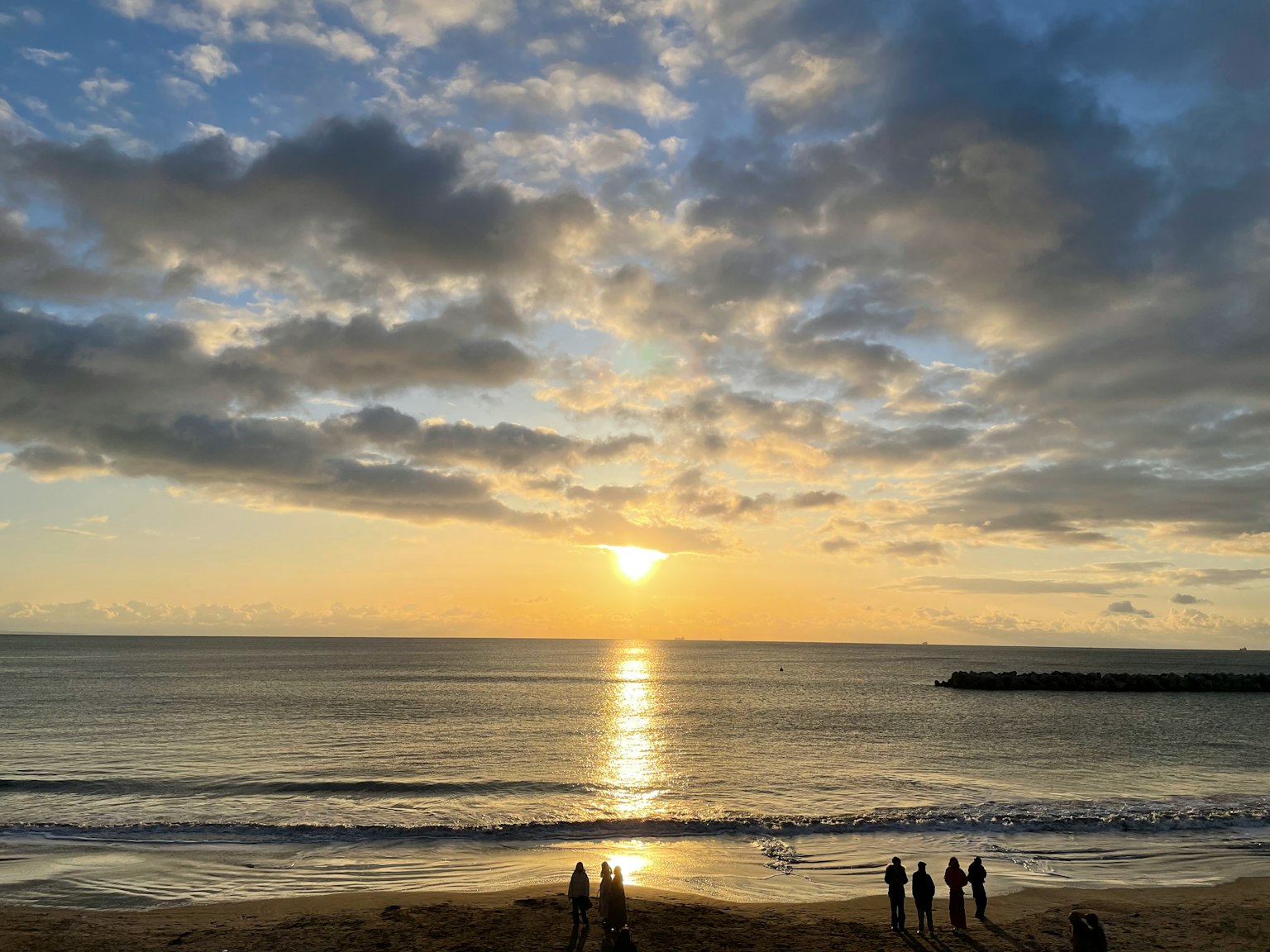 Bellissimo tramonto sull'oceano con nuvole persone che osservano dalla spiaggia