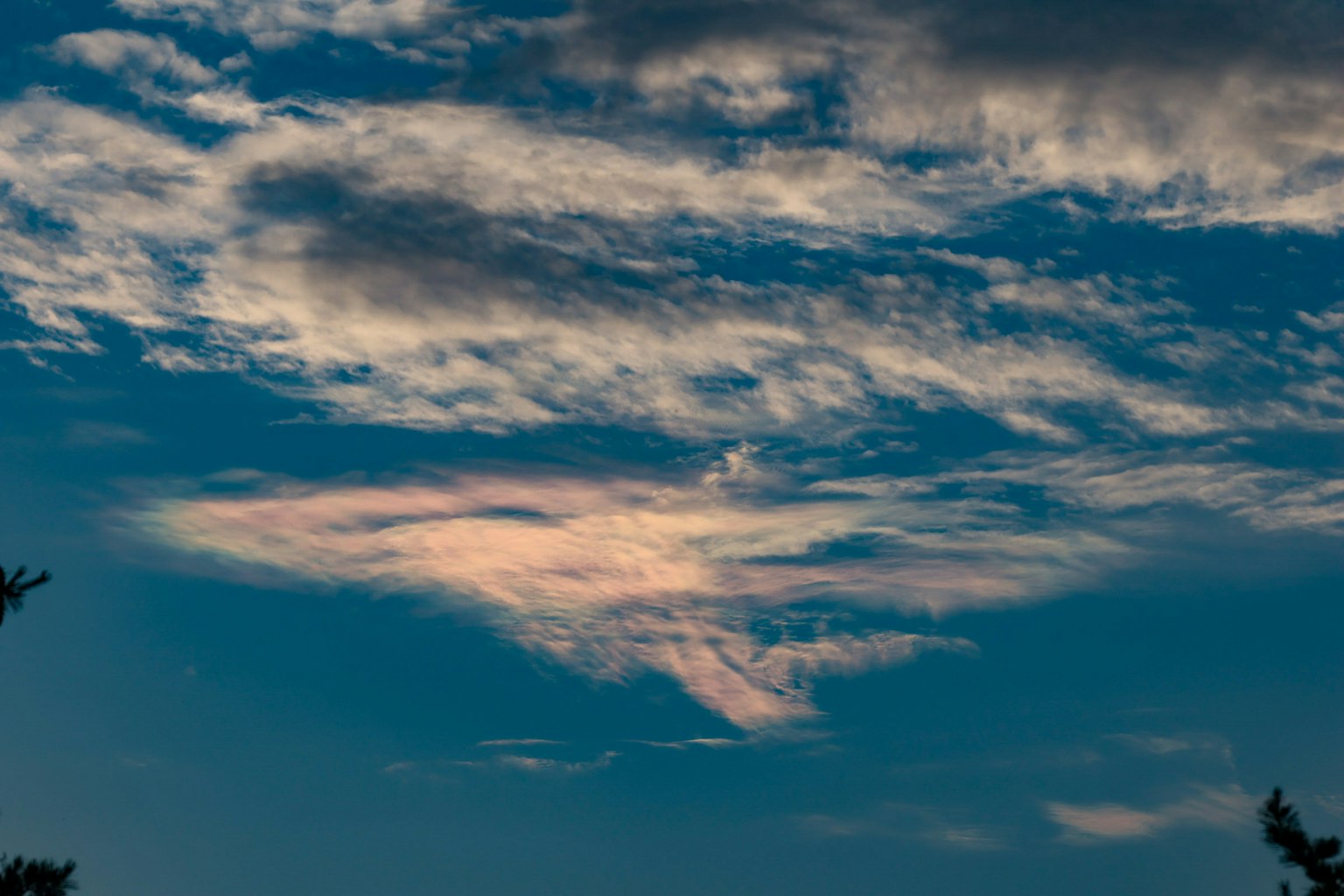 Un paesaggio con nuvole dai toni arcobaleno su uno sfondo blu