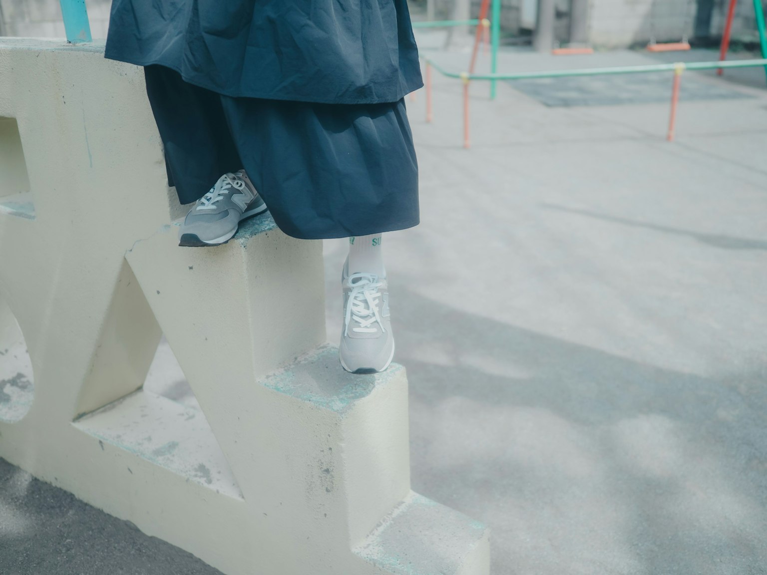 青いスカートを履いた人物が遊び場の白いブロックの上に立っている